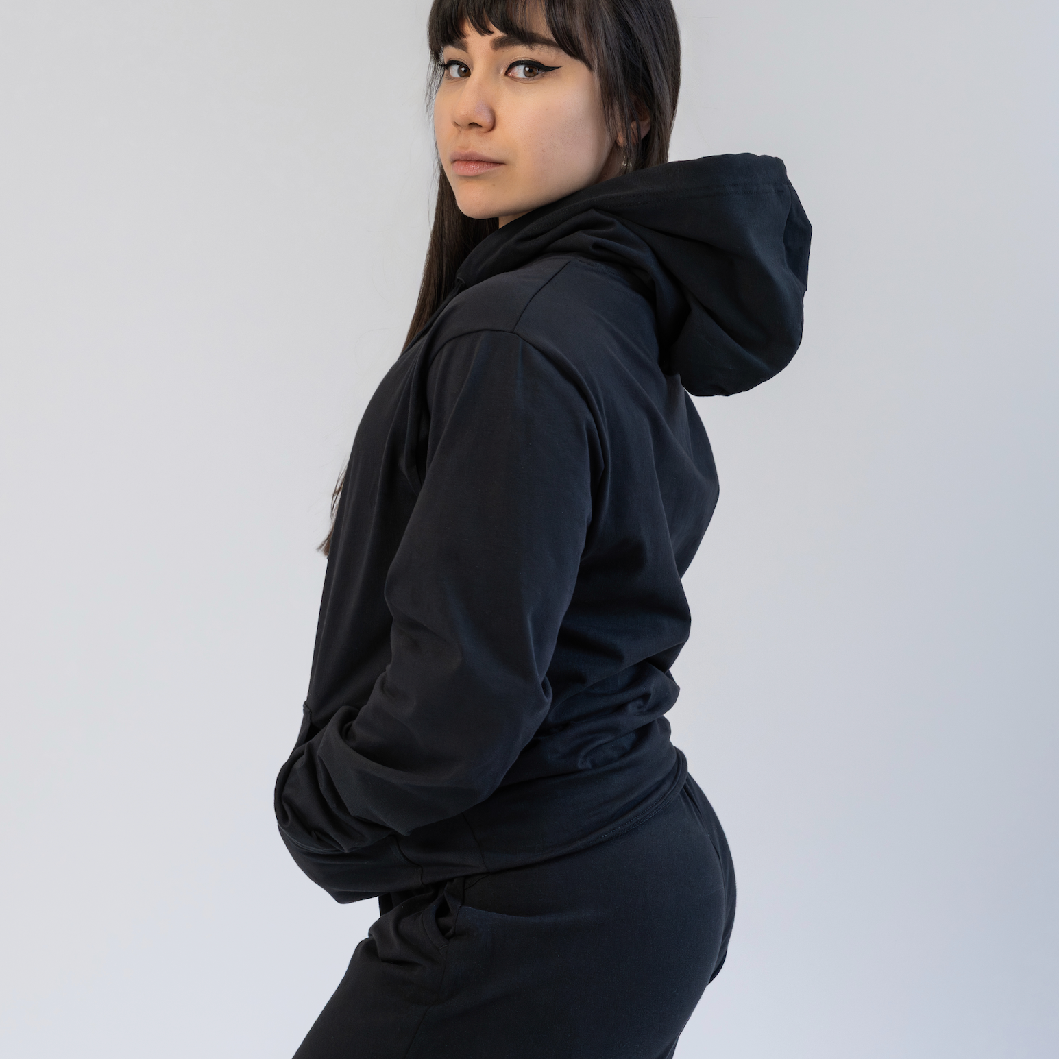 Person wearing a black hoodie and shorts on a white background