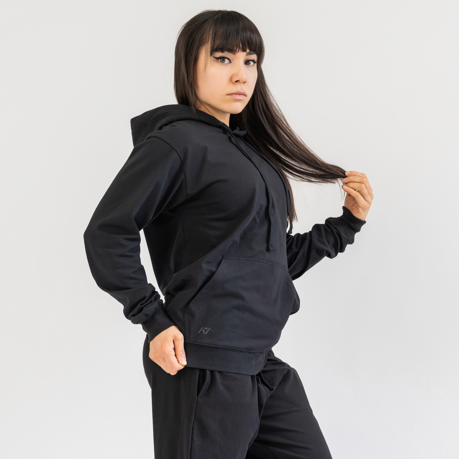 Person wearing a black hoodie and pants on a white background