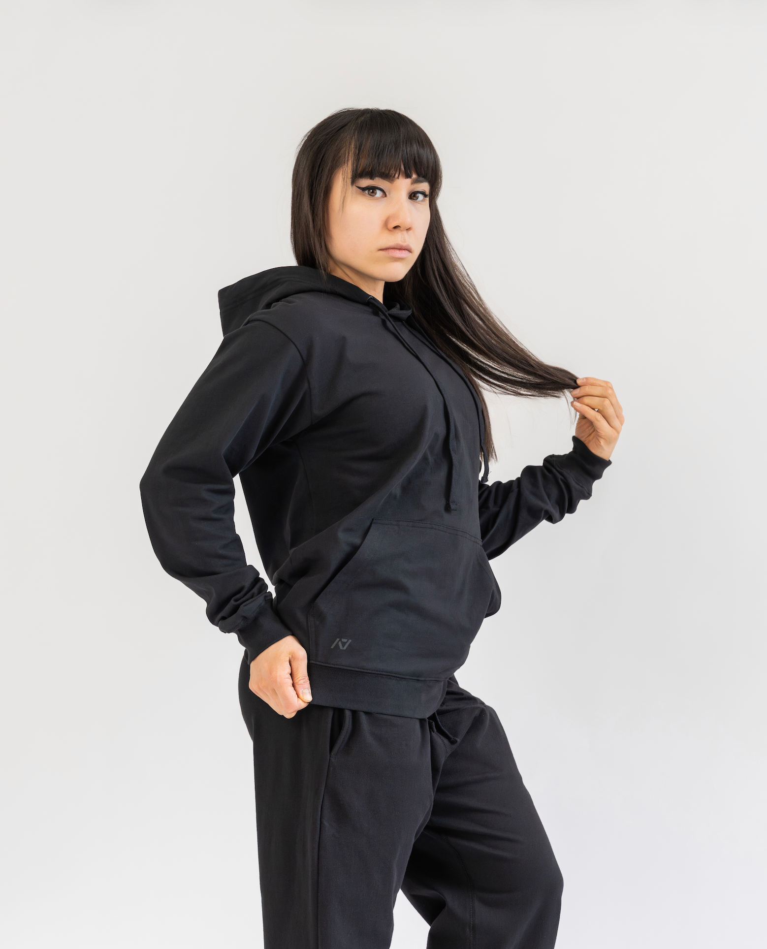 Person wearing a black hoodie and pants on a white background