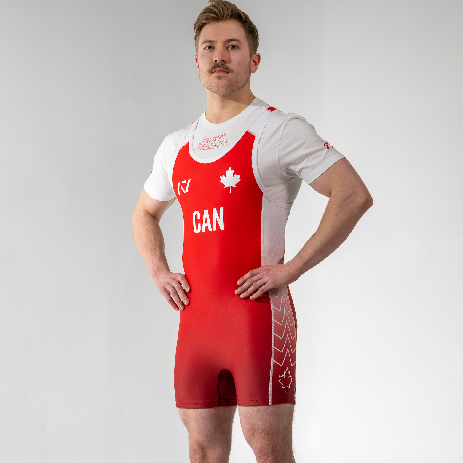 Person wearing a red and white powerlifting singlet with 'CAN' and a maple leaf on a plain background