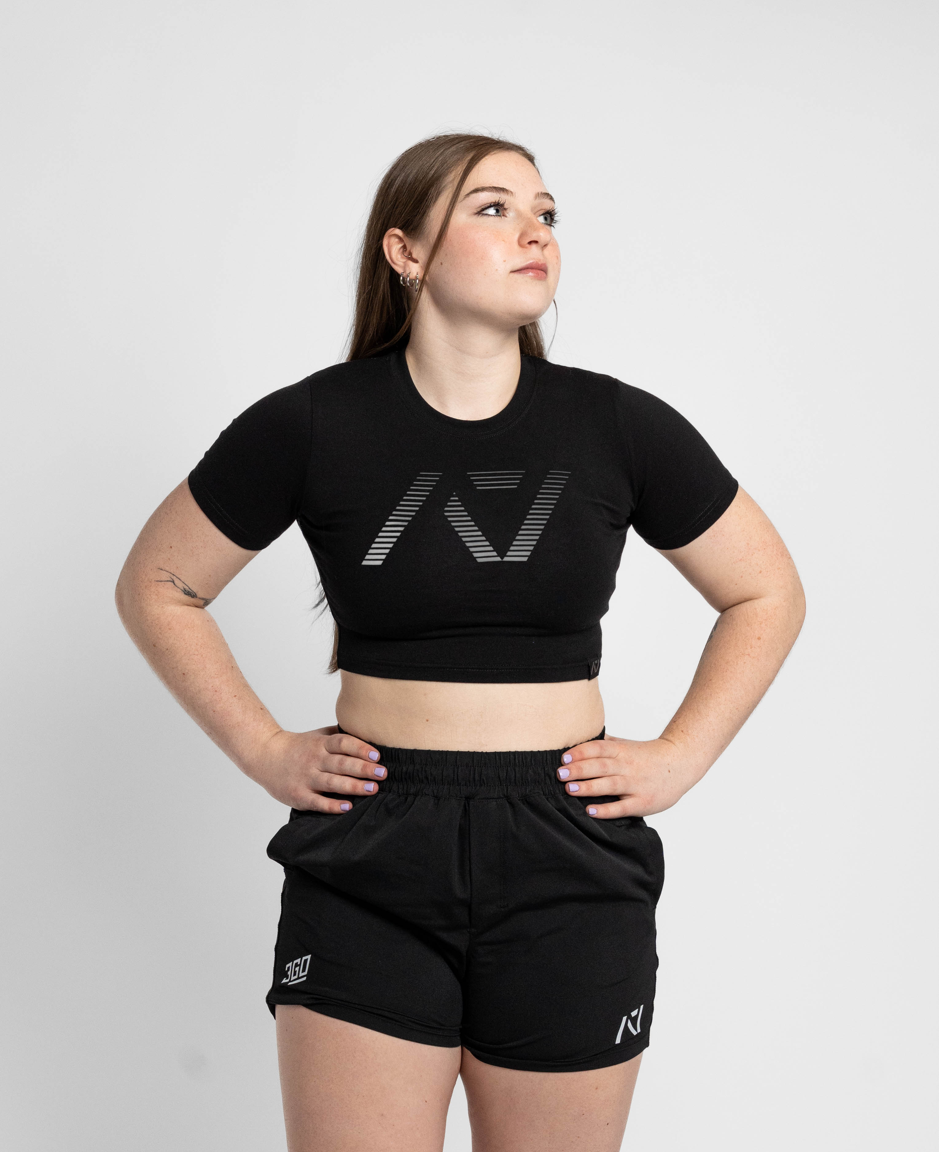Person wearing a black crop top and shorts with a logo on a white background