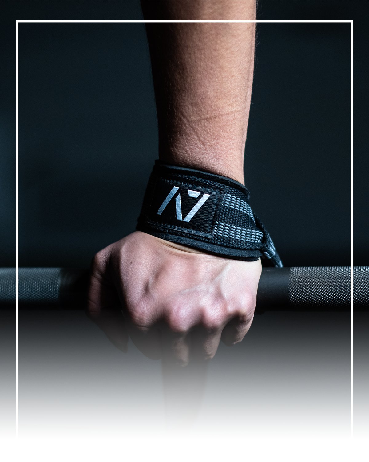 Hand wearing a black pull straps for deadlifts with a logo, holding a barbell on a dark background