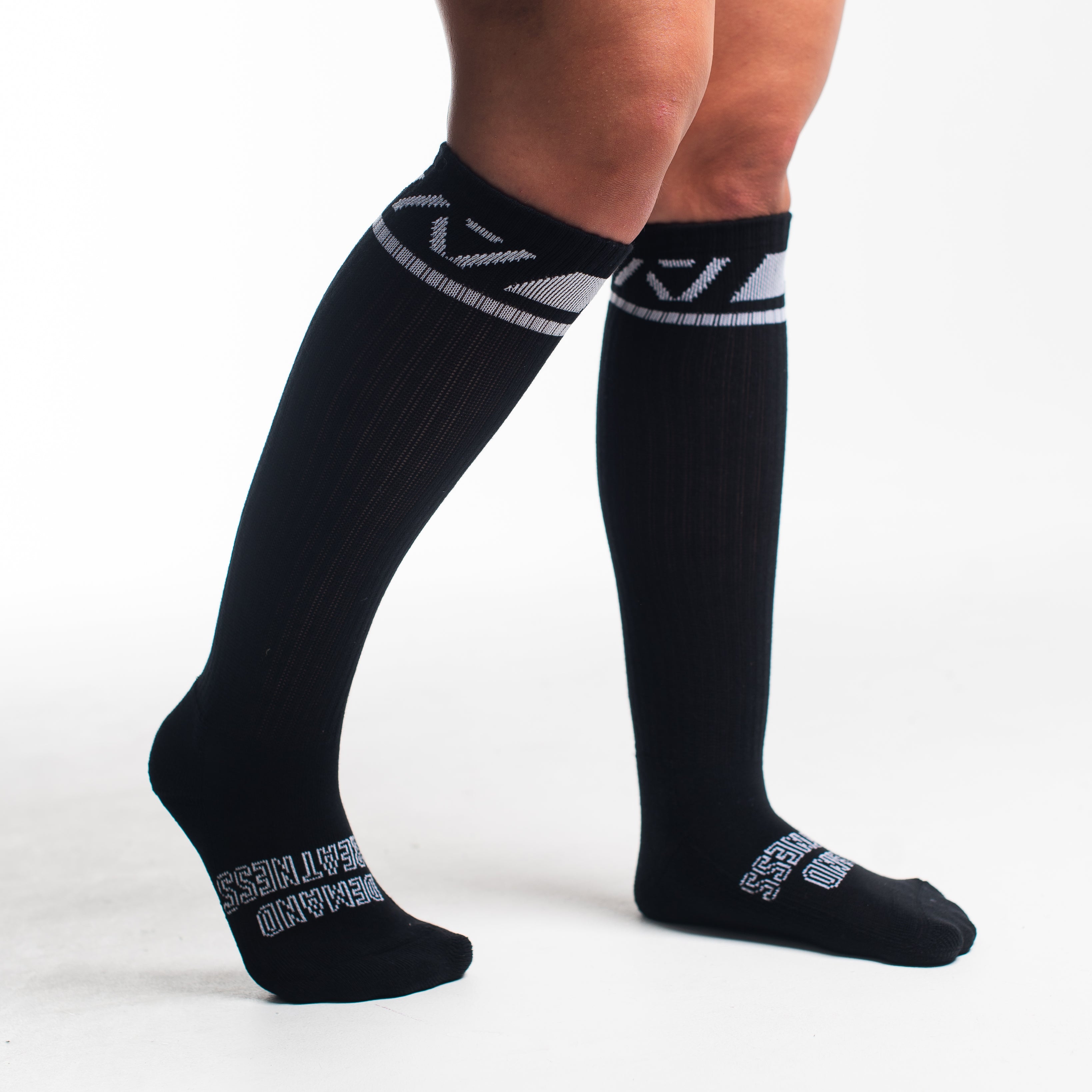 Side profile of A7 Deadlift Socks in Domino Black, highlighting the "Demand" and "Greatness" logos on each side.