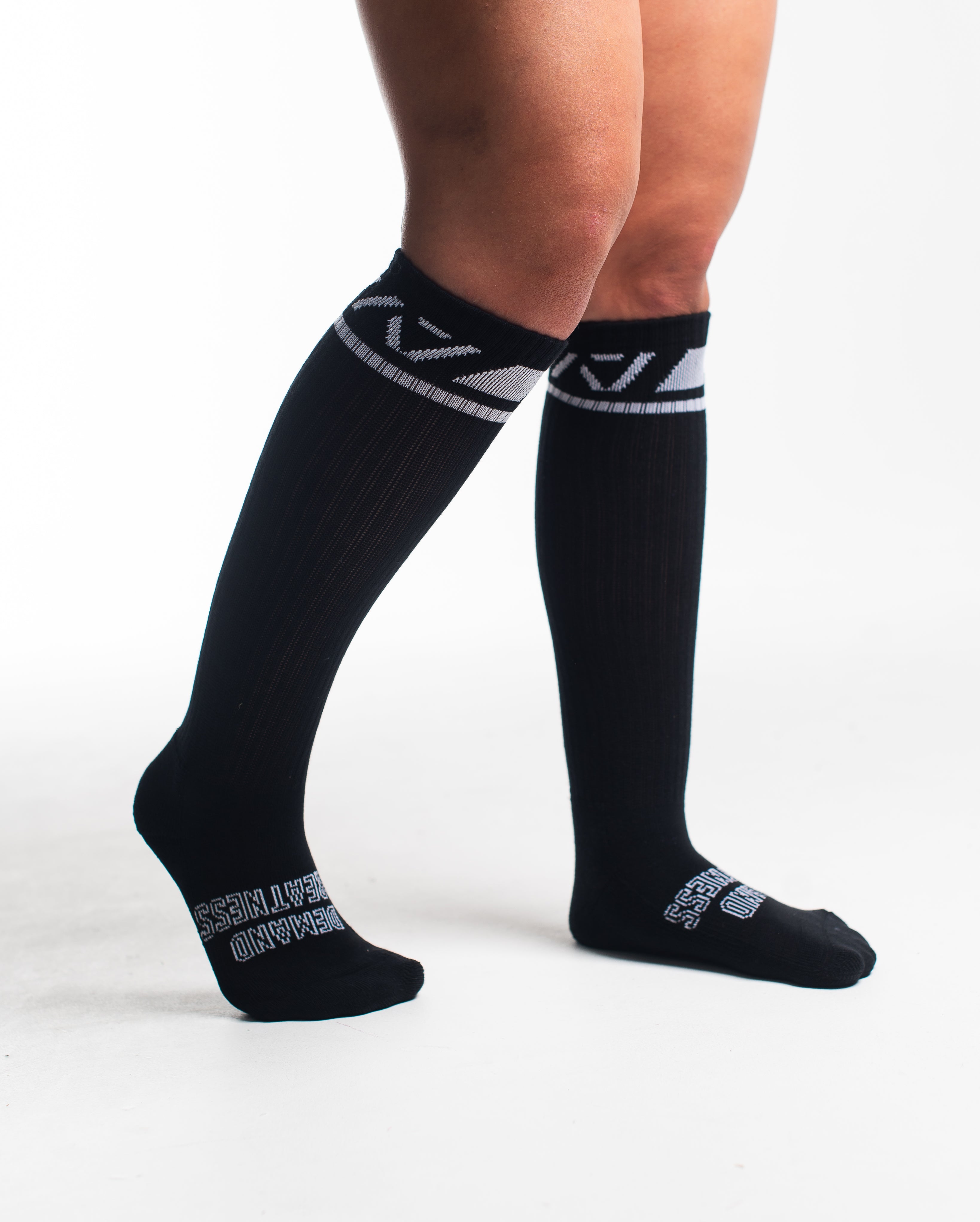 Side profile of A7 Deadlift Socks in Domino Black, highlighting the "Demand" and "Greatness" logos on each side.