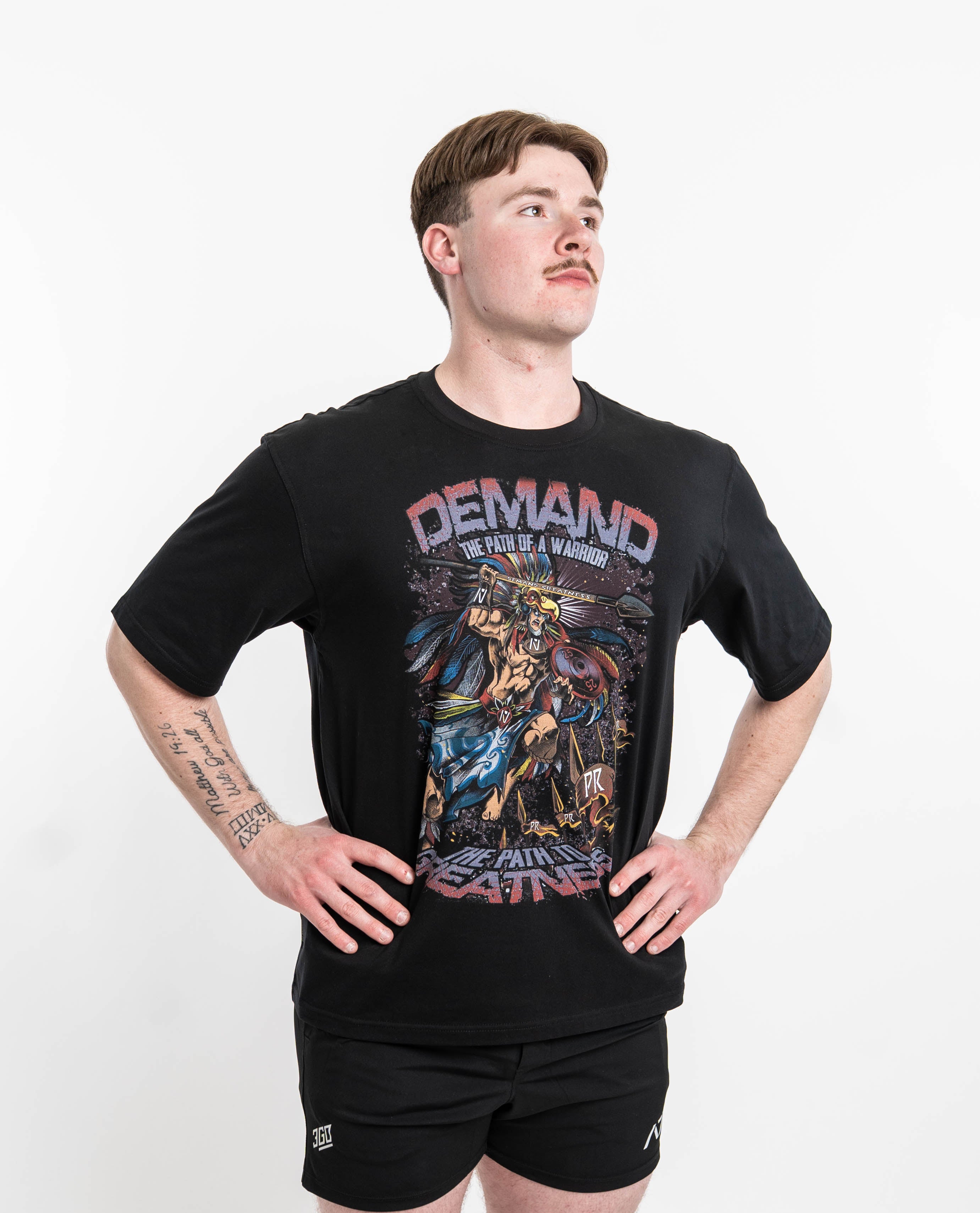 ront view of Aztec Warrior Over-Fit Unisex Shirt showcasing the detailed Aztec warrior design with eagle headdress and "Demand Greatness" spear.