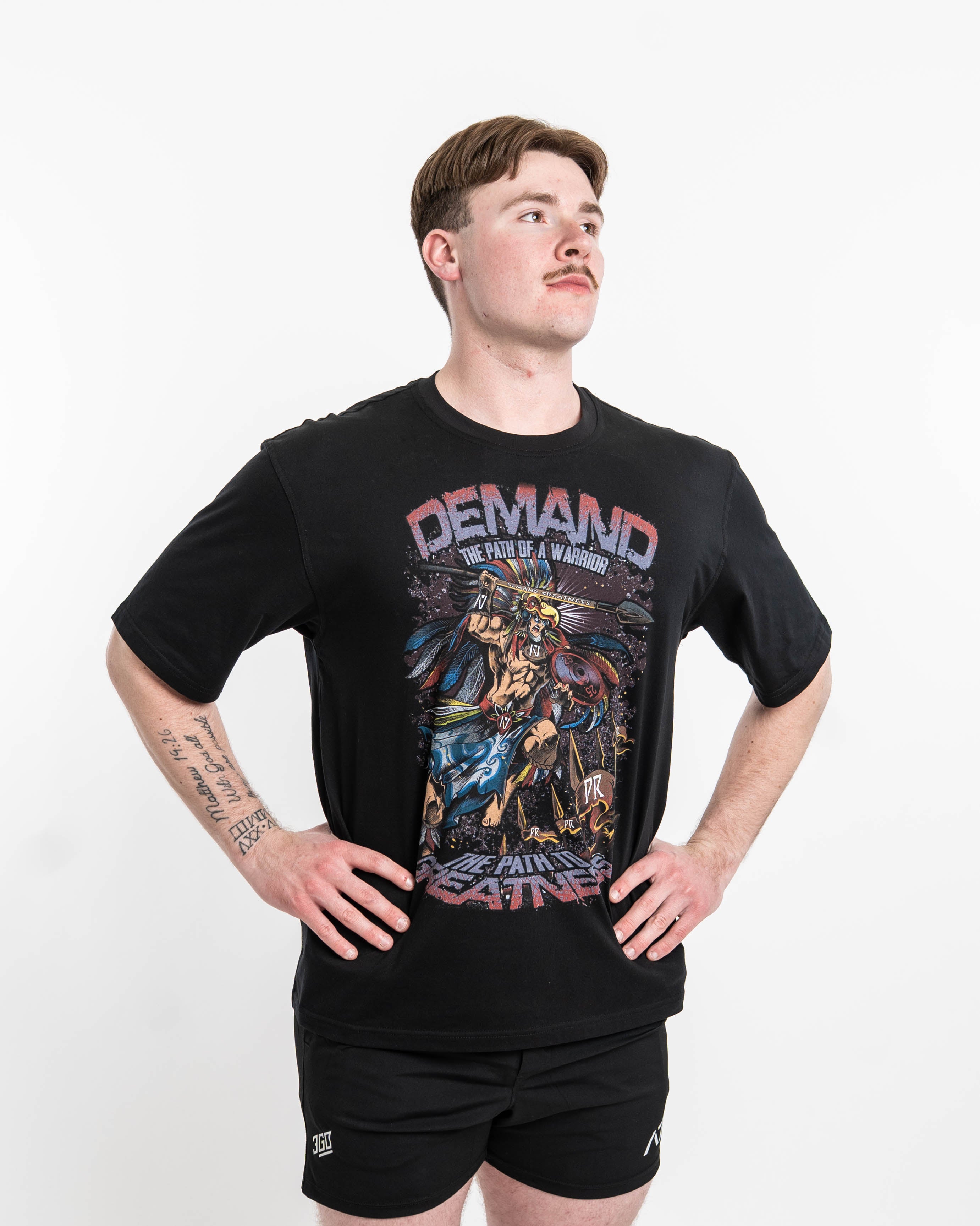 ront view of Aztec Warrior Over-Fit Unisex Shirt showcasing the detailed Aztec warrior design with eagle headdress and "Demand Greatness" spear.