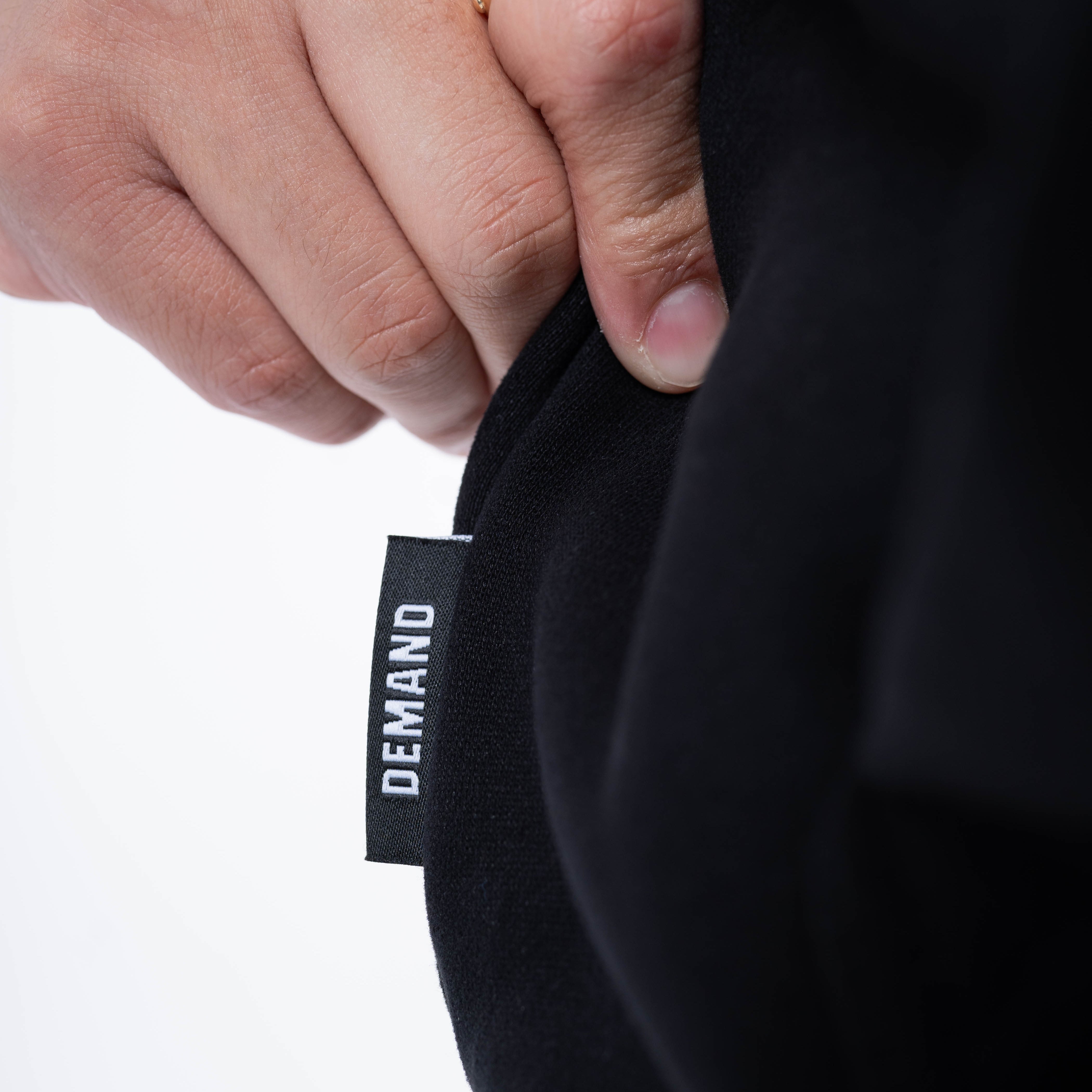 Close-up of the A7 hem tag stitched on the side seam of the Built By Hoodie – Black, highlighting premium branding and construction detail.