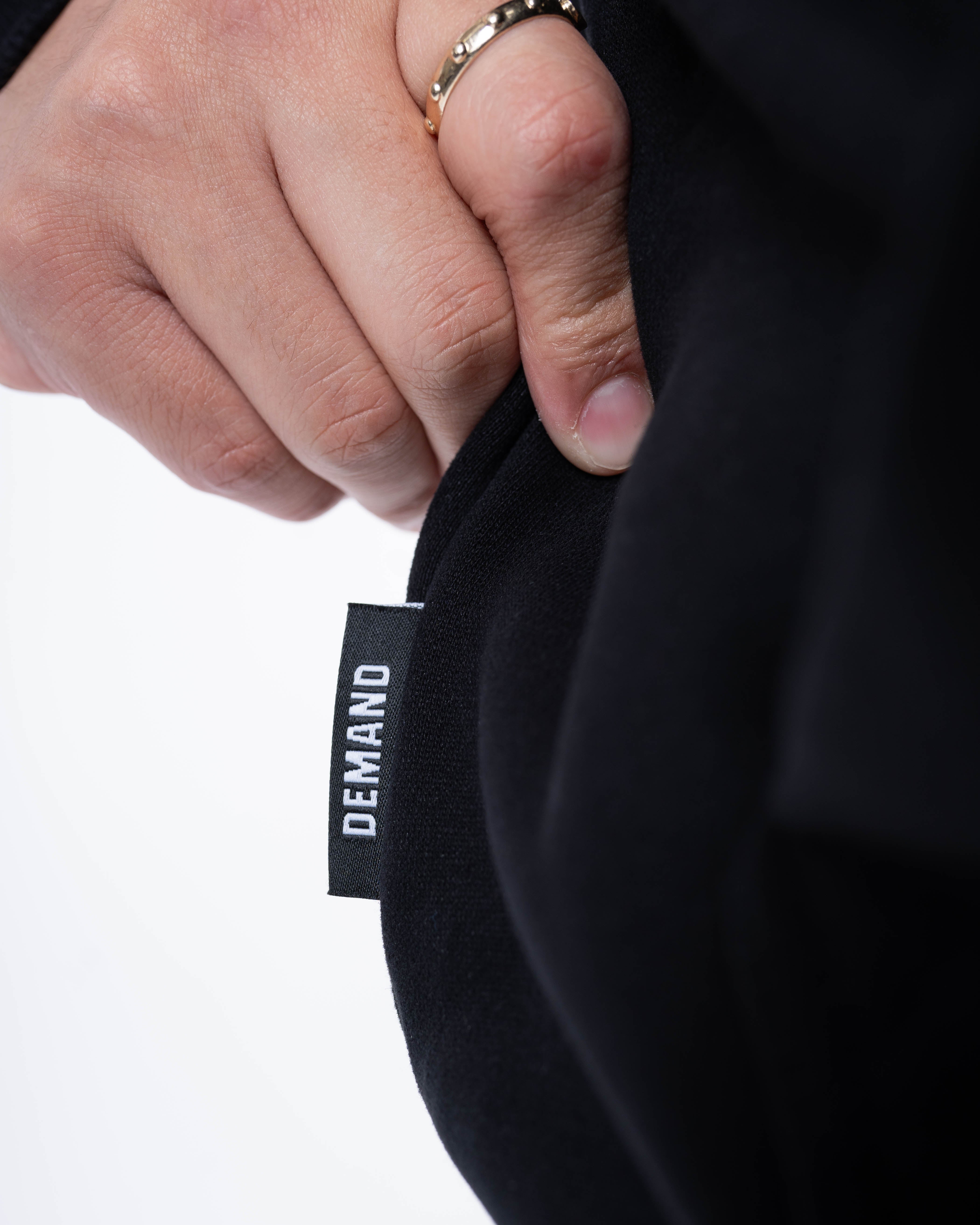 Close-up of the A7 hem tag stitched on the side seam of the Built By Hoodie – Black, highlighting premium branding and construction detail.