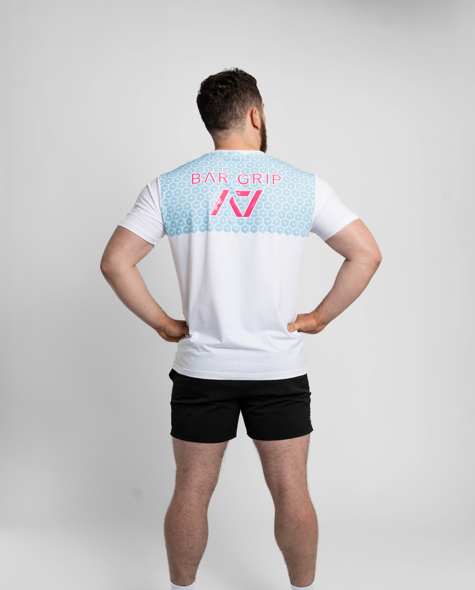 Person wearing a white t-shirt with a7 Bar Grip on the back against a gray background