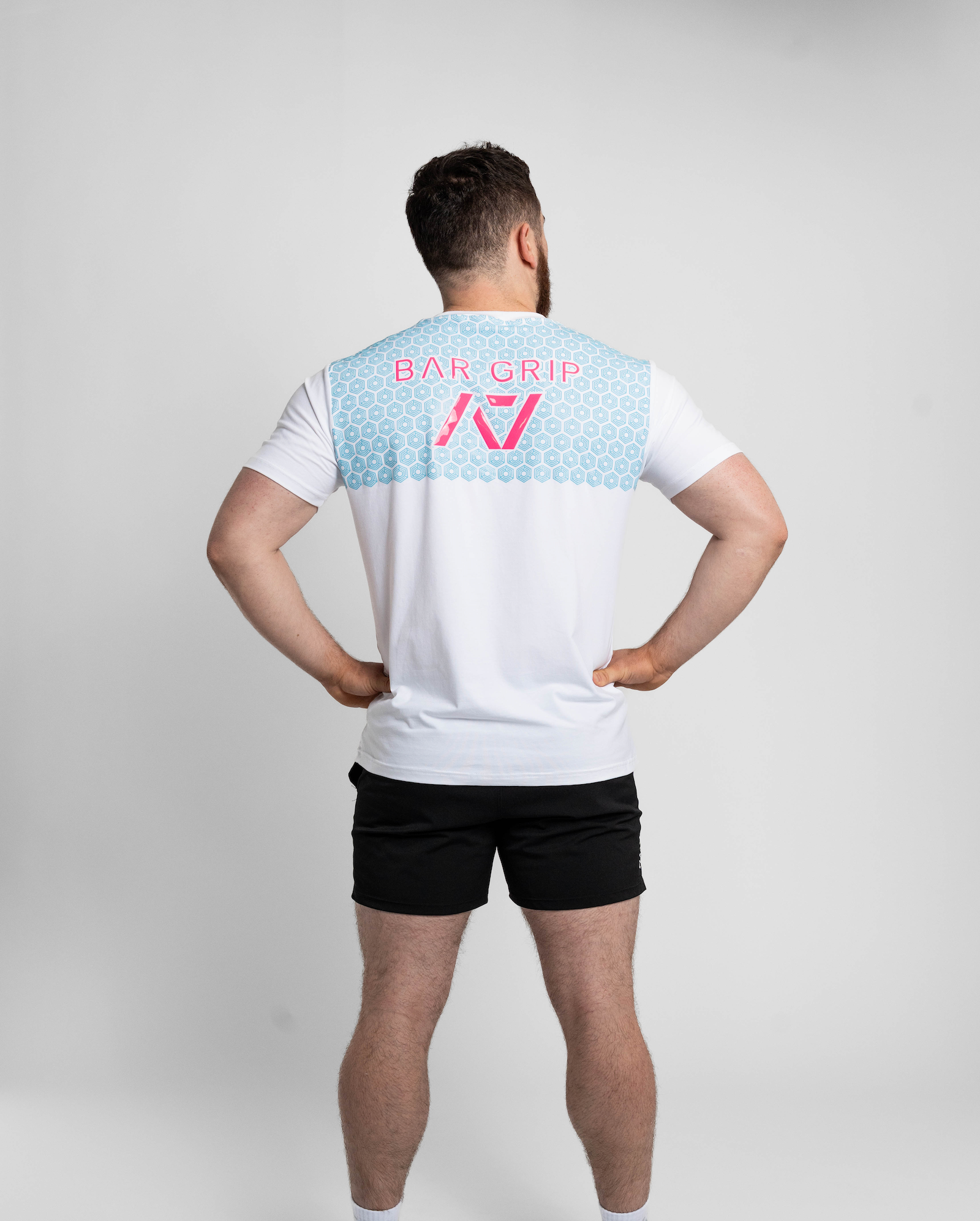 Person wearing a white t-shirt with a7 Bar Grip on the back against a gray background