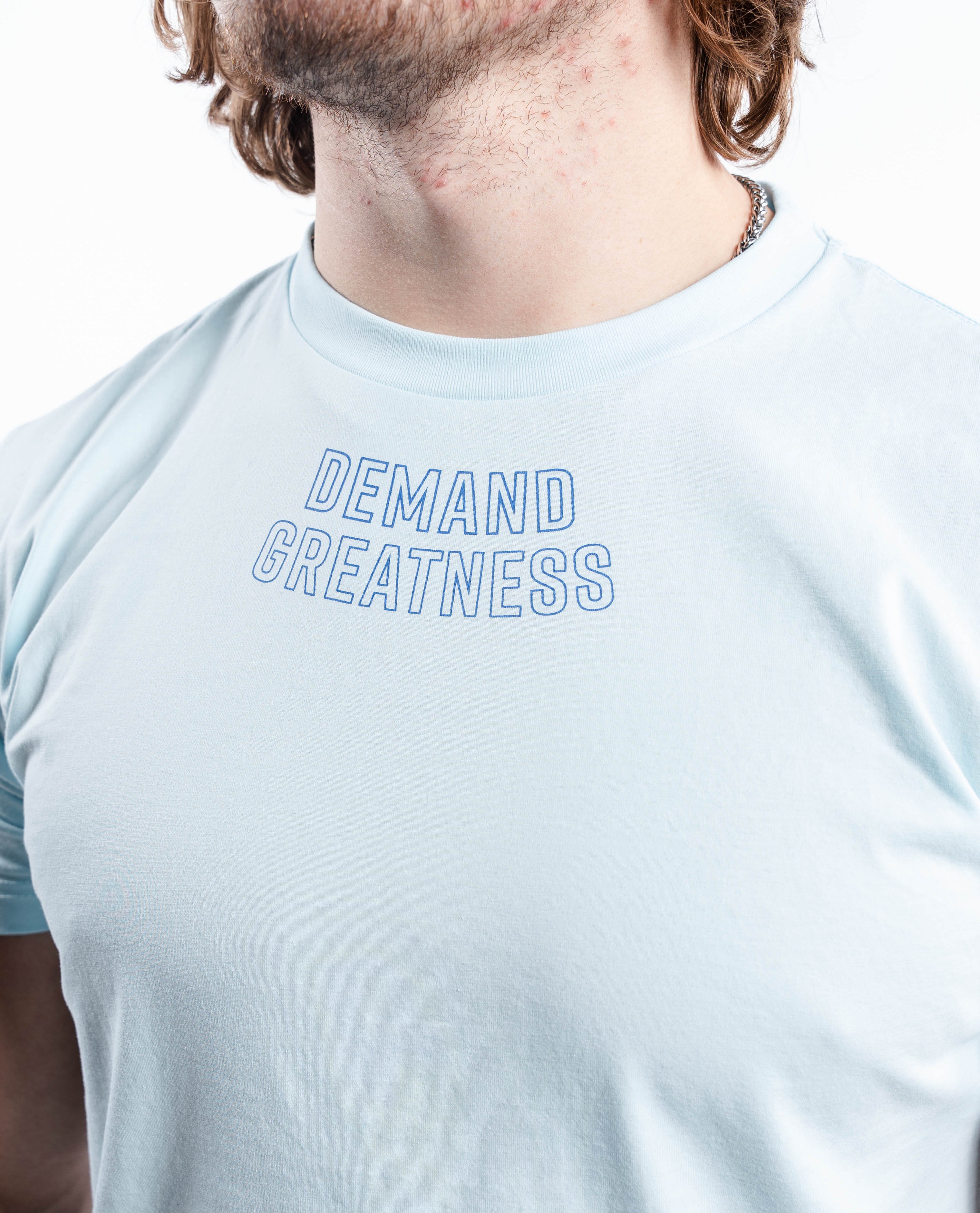 Close-up of “Demand Greatness” chest print on the Cyanite True-Fit Men’s Meet Shirt, featuring bold, textured lettering across the upper torso.