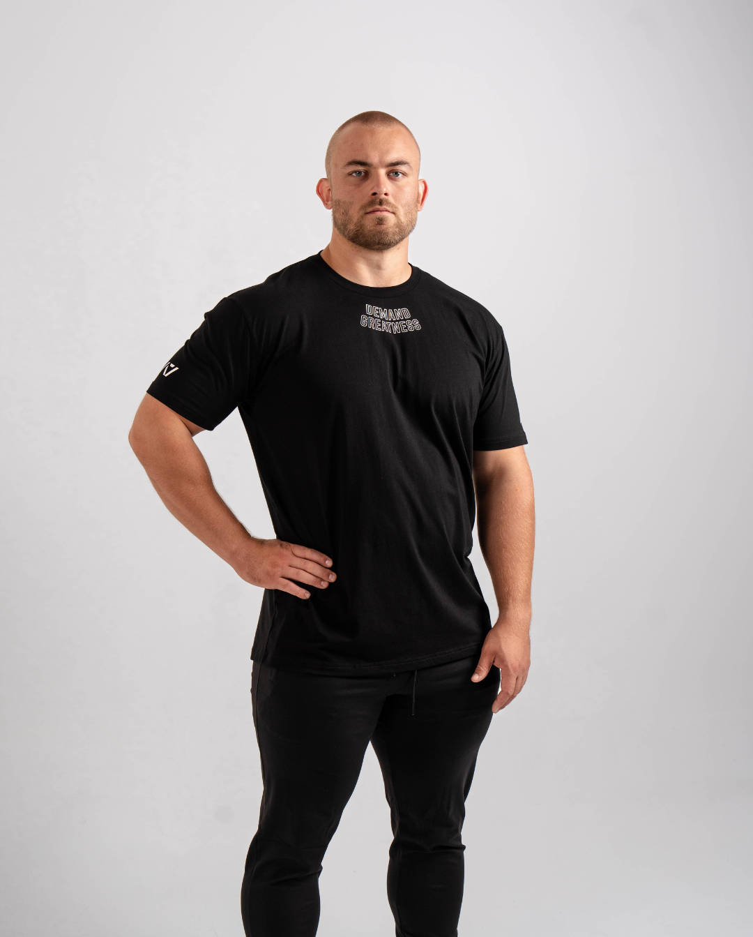 Front view of the Domino True‑Fit Meet Shirt showcasing the “Demand Greatness” print and athletic torso fit.