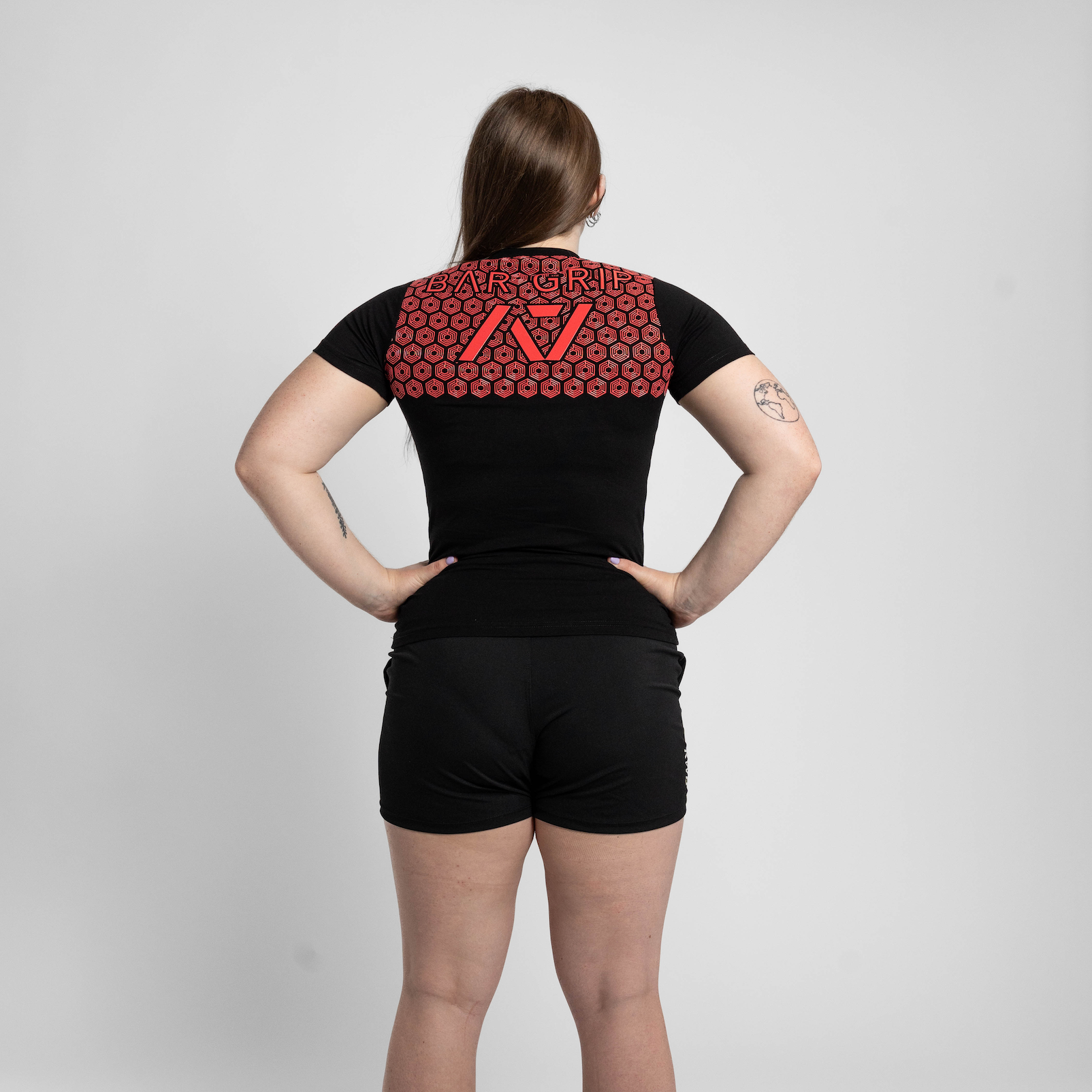 Person wearing a black t-shirt with a red bar grip on the back against a white background