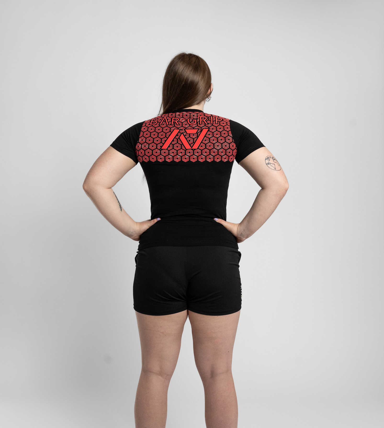 Person wearing a black t-shirt with a red bar grip on the back against a white background