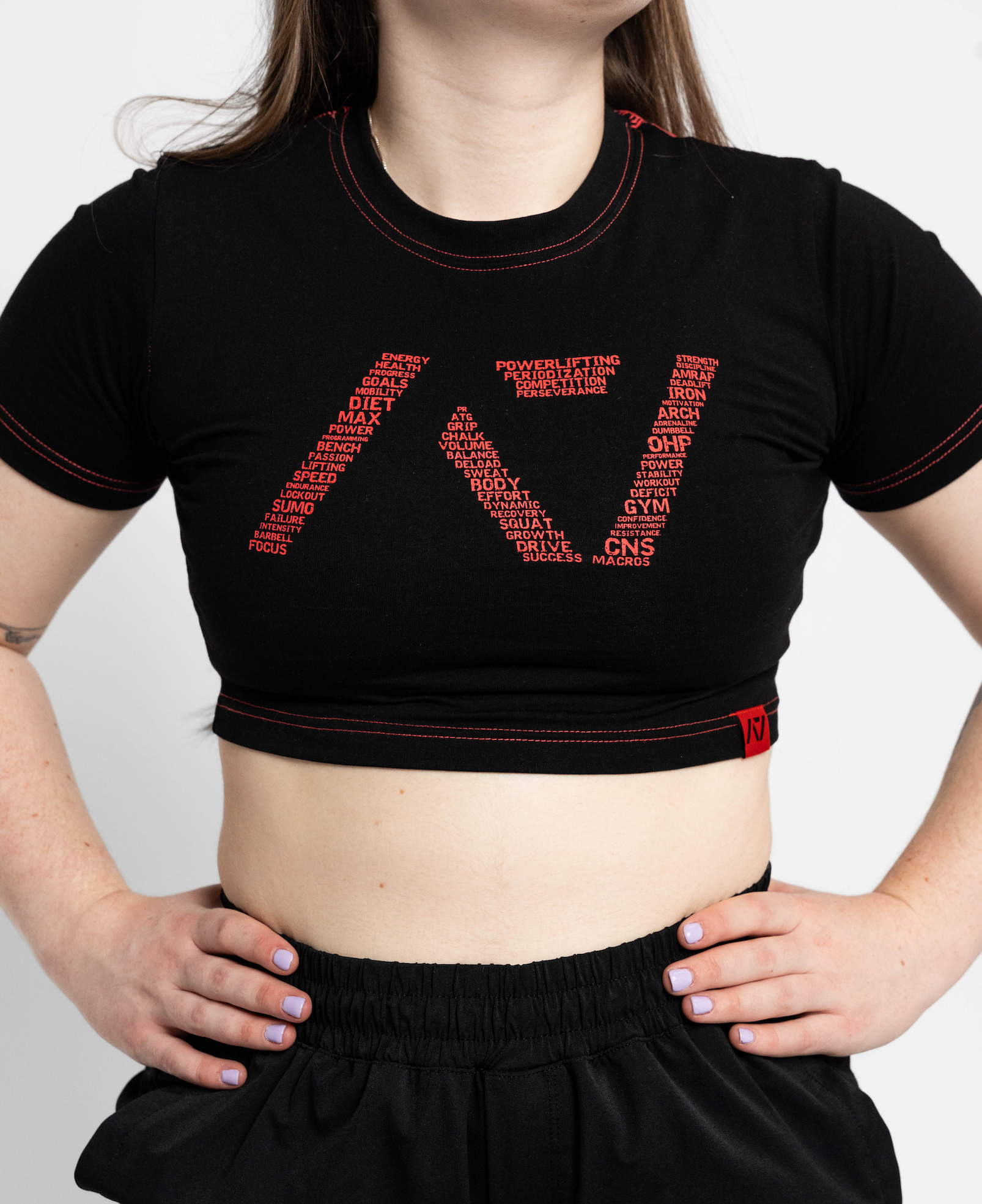 Person wearing a black crop top with red text design on a plain background