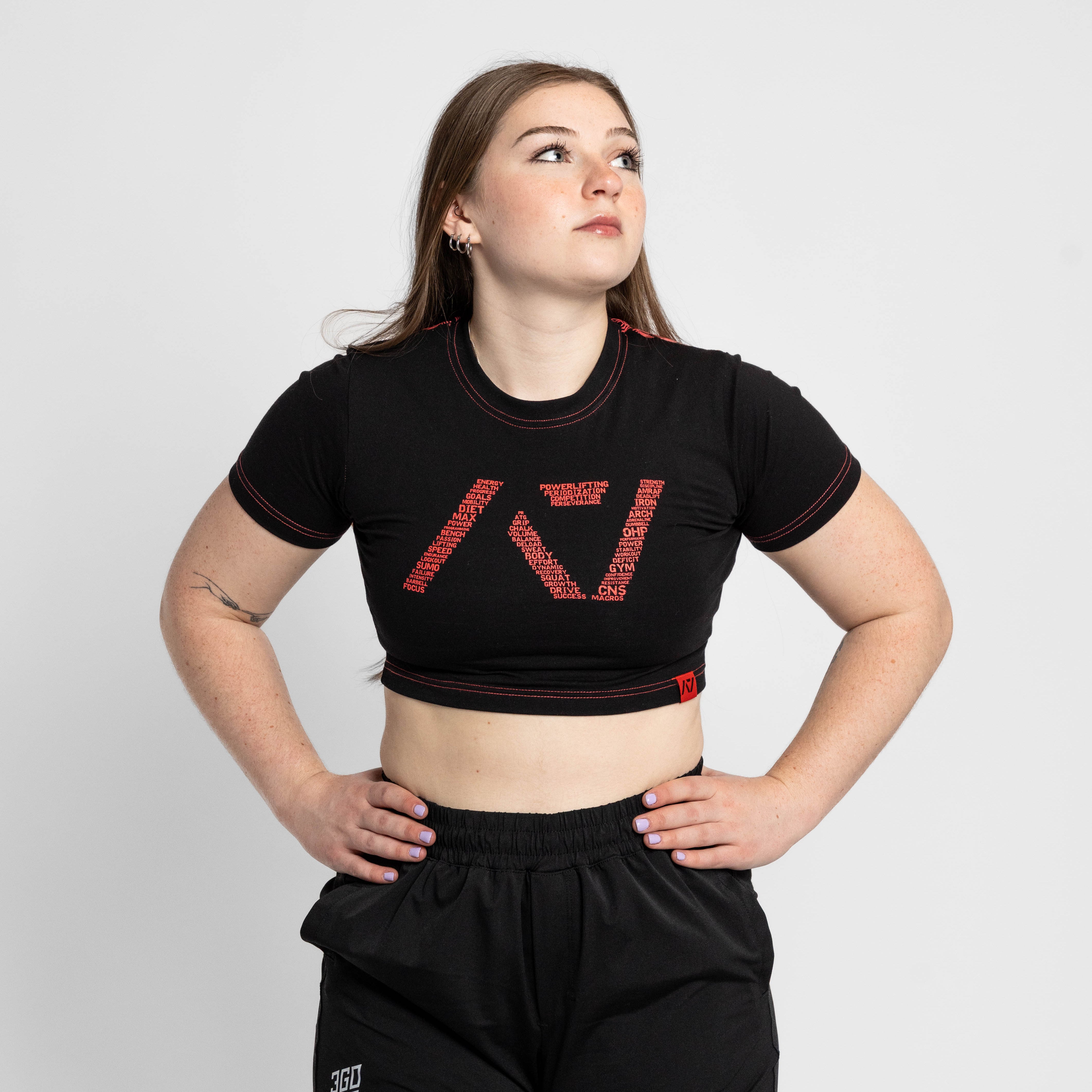 Woman wearing a black crop top and shorts with a brand logo on a white background