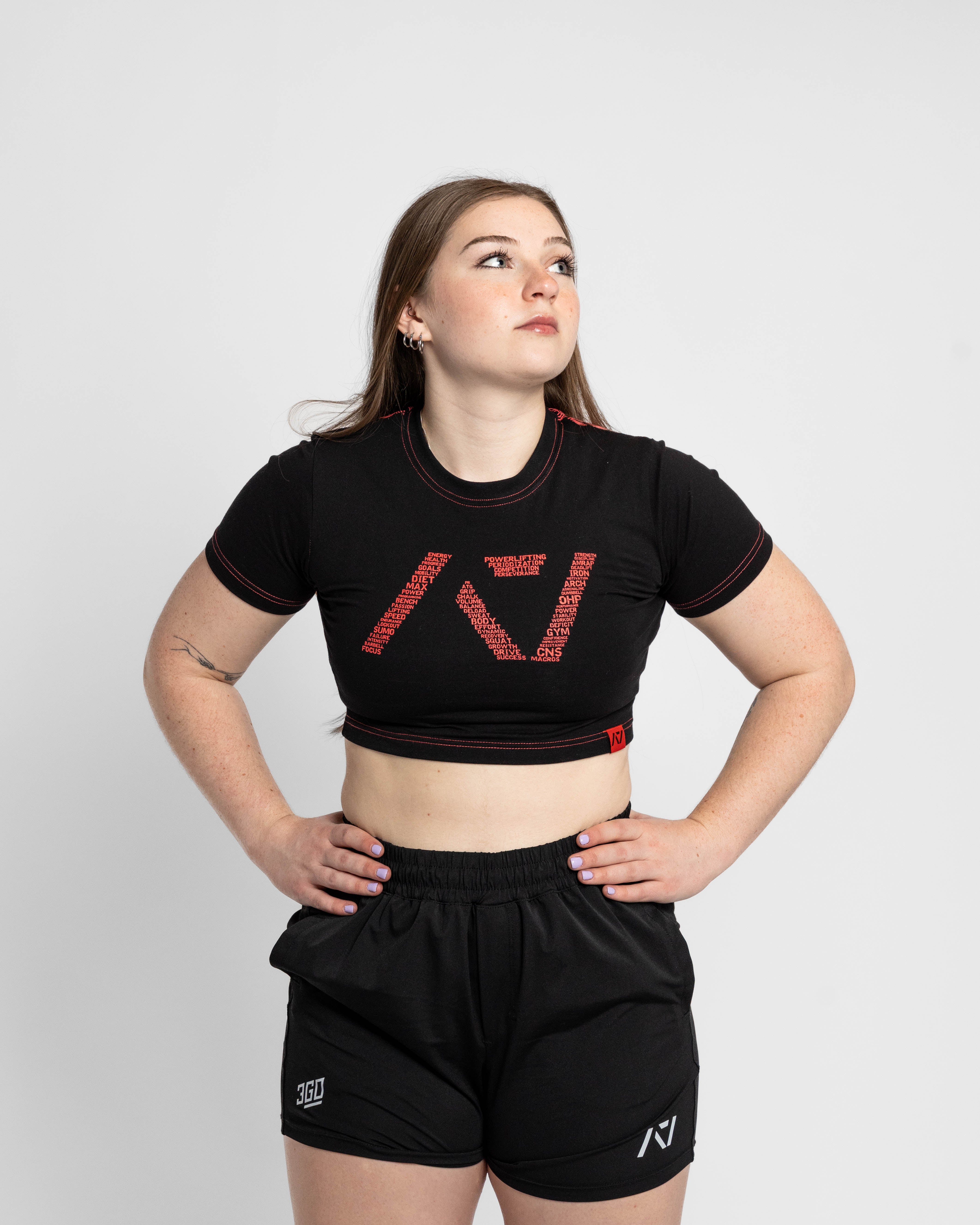 Woman wearing a black crop top and shorts with a brand logo on a white background