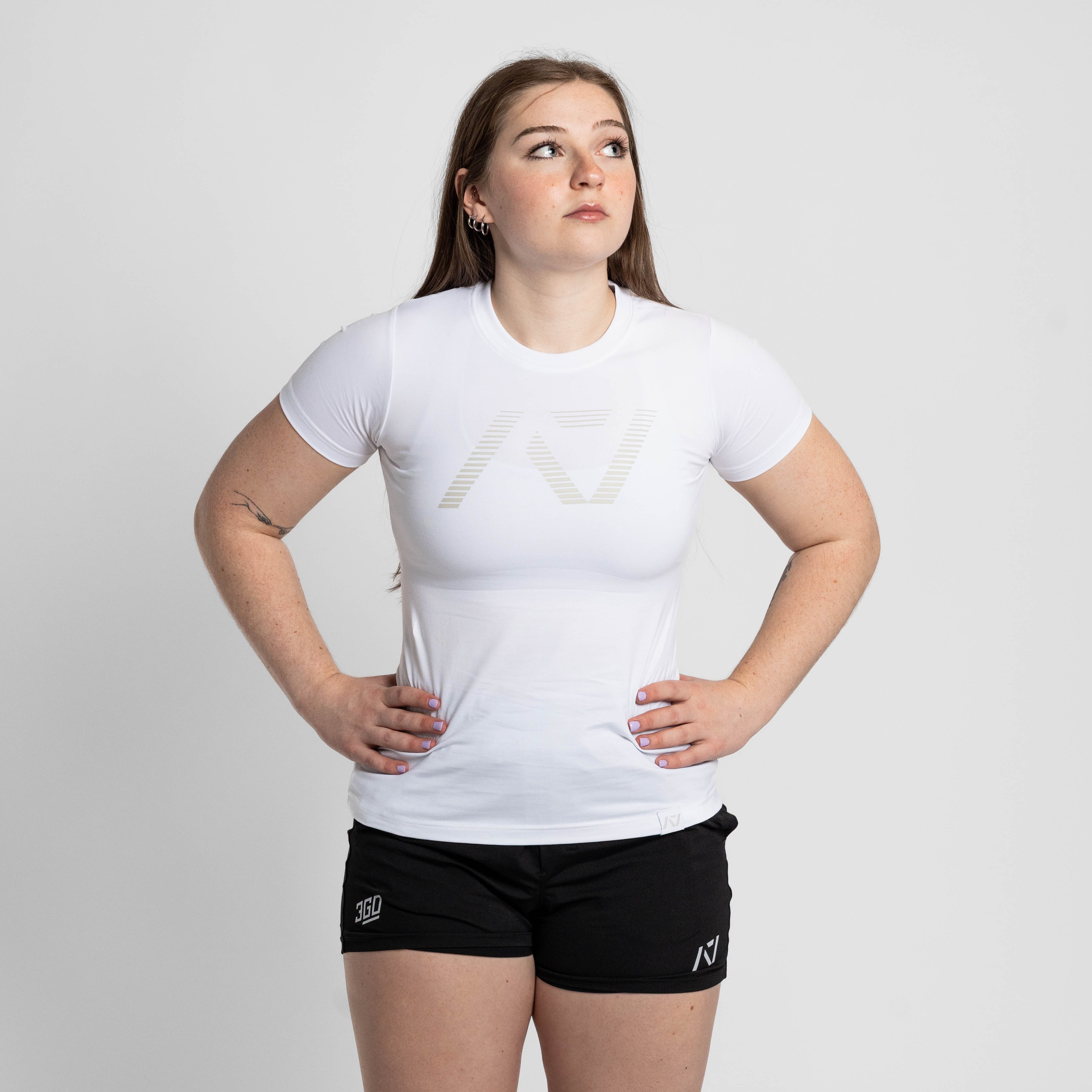 Person wearing a white t-shirt and black shorts with a logo on a plain background