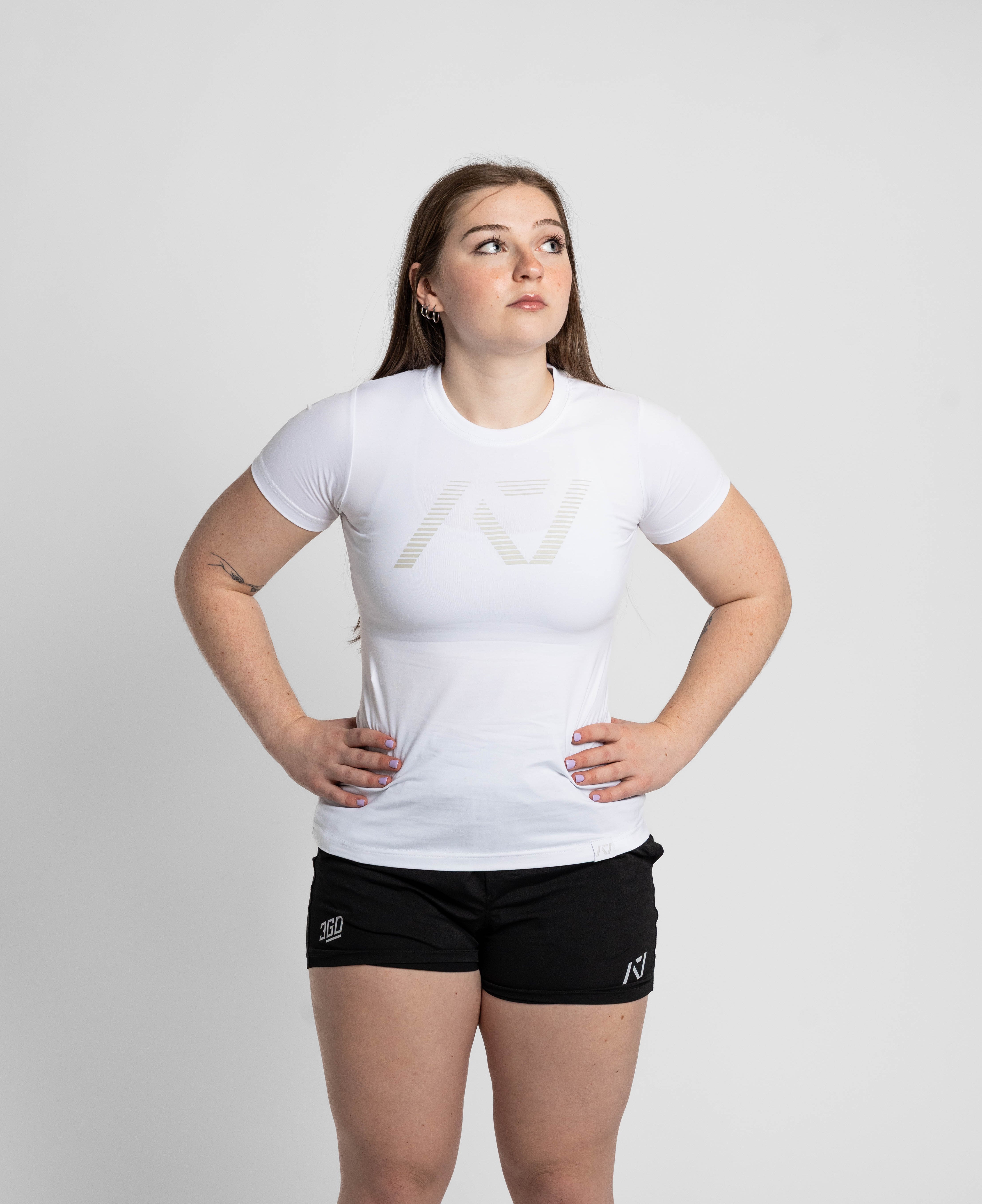Person wearing a white t-shirt and black shorts with a logo on a plain background