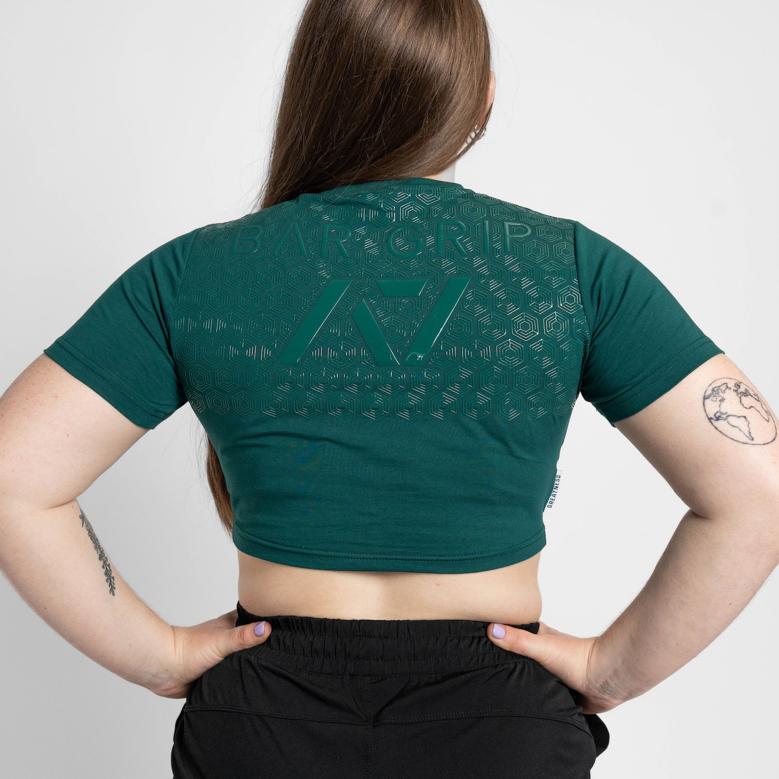 Person wearing a green crop top with a bar grip on a plain background