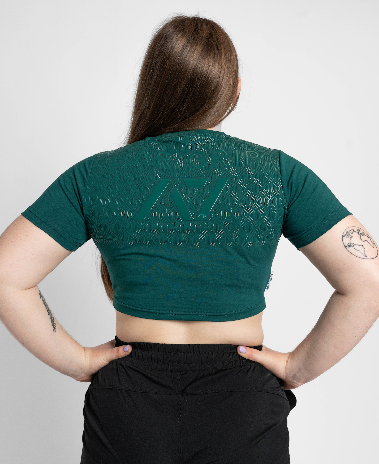Person wearing a green crop top with a bar grip on a plain background