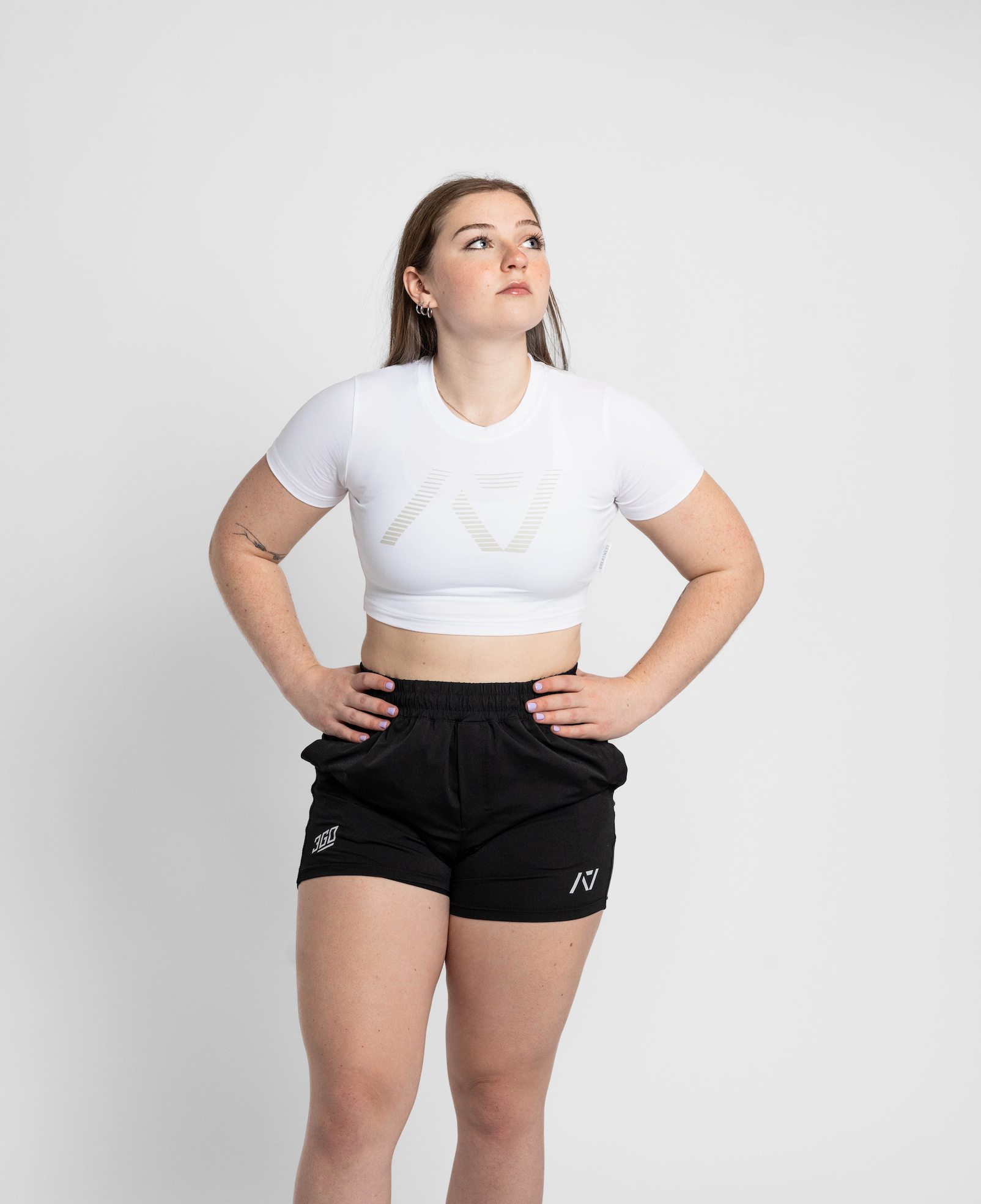 Person wearing a white crop top and black shorts on a plain background