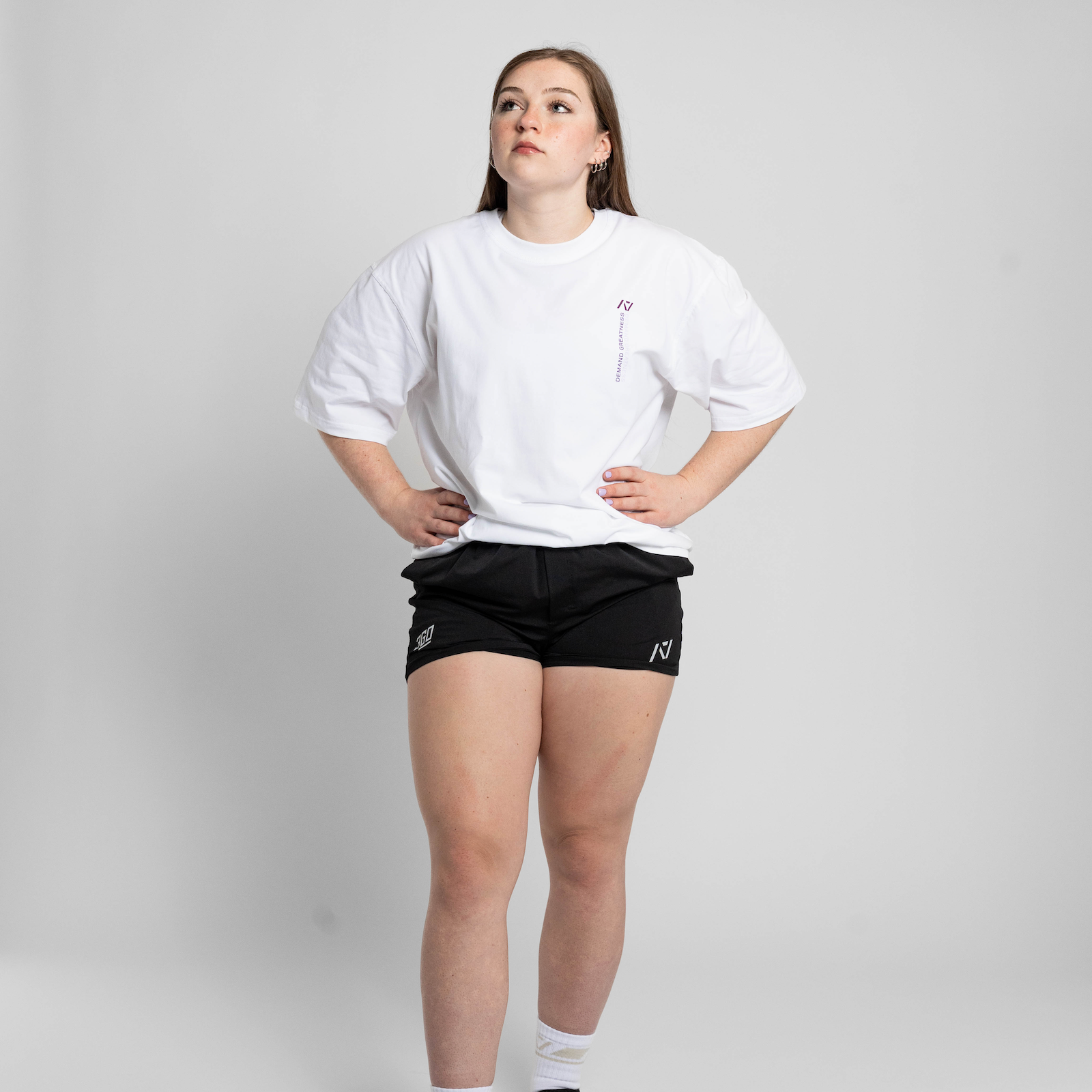 Person wearing a white oversized t-shirt and black shorts on a plain background