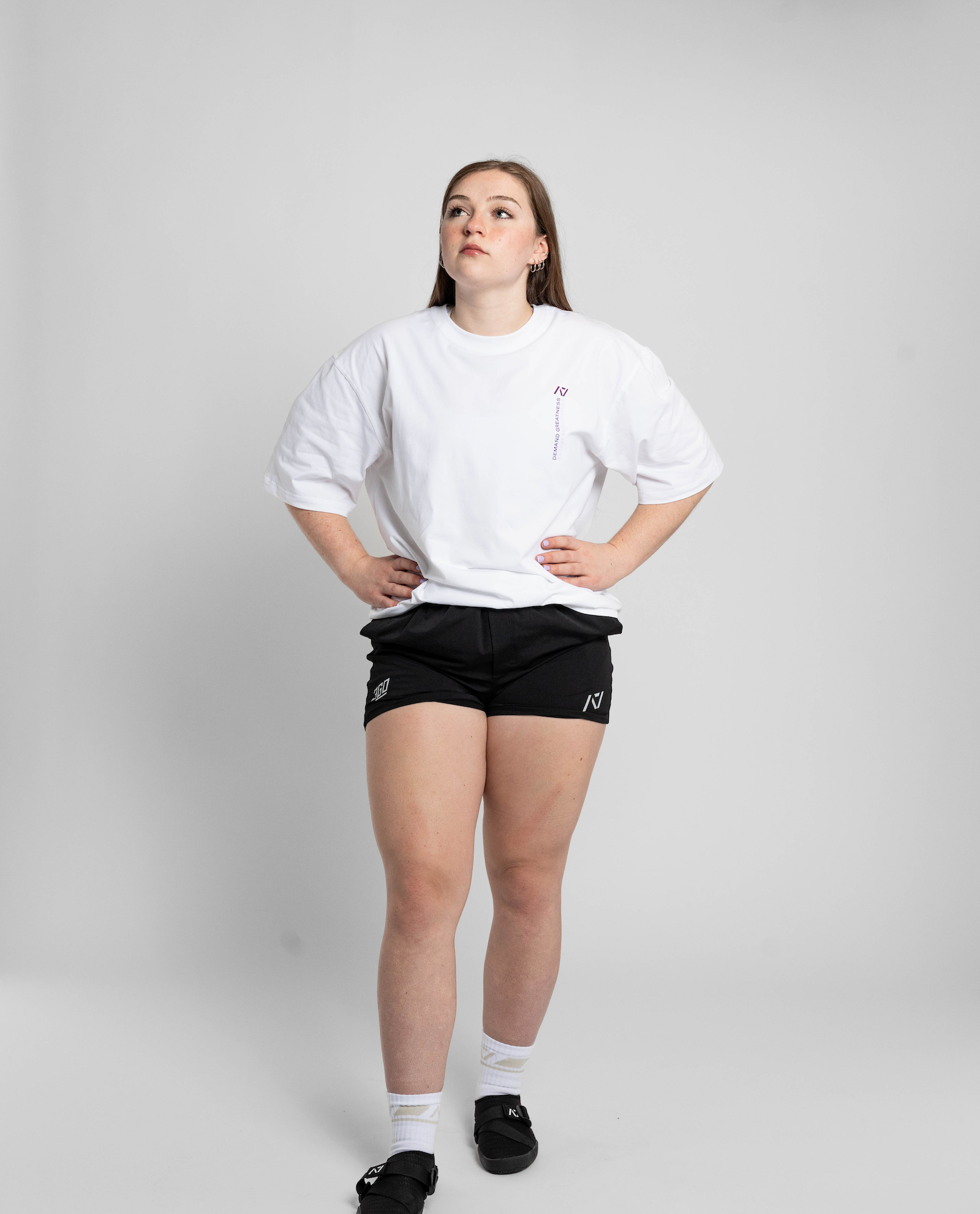 Person wearing a white oversized t-shirt and black shorts on a plain background