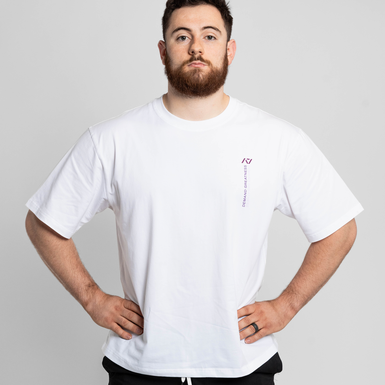 Man wearing a white oversized t-shirt with a small logo on a plain background