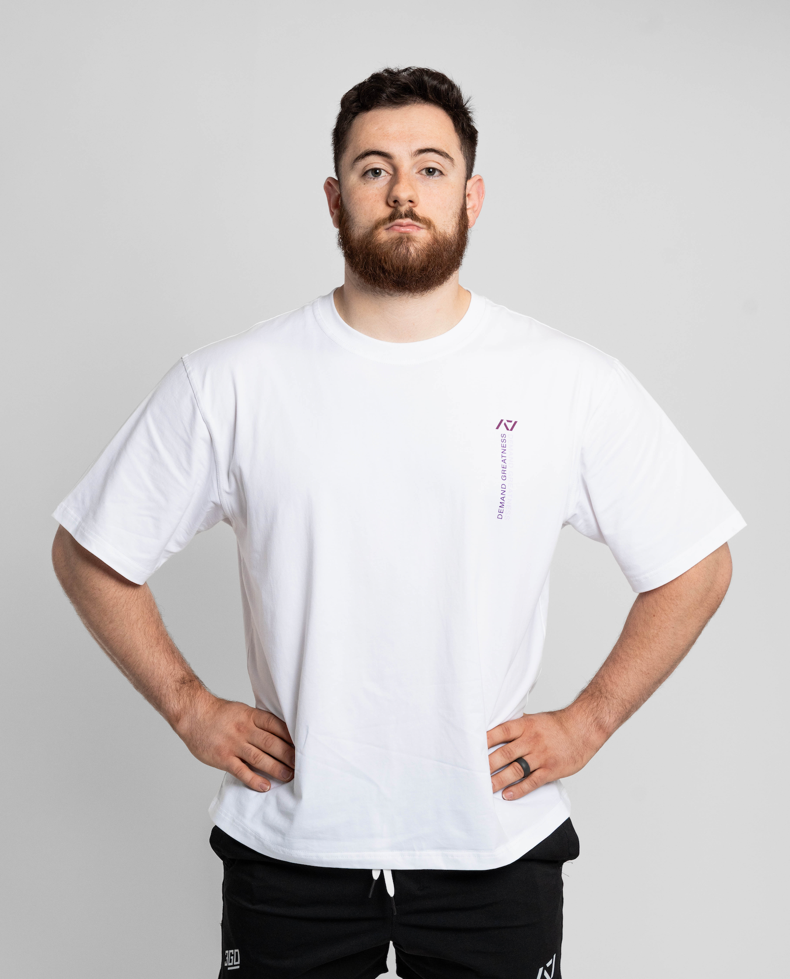 Man wearing a white oversized t-shirt with a small logo on a plain background