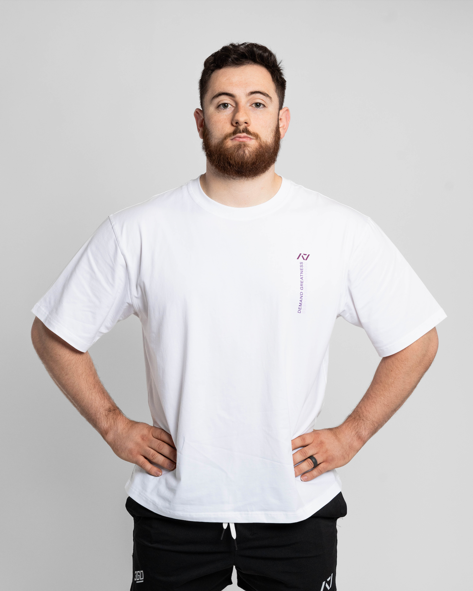 Man wearing a white oversized t-shirt with a small logo on a plain background