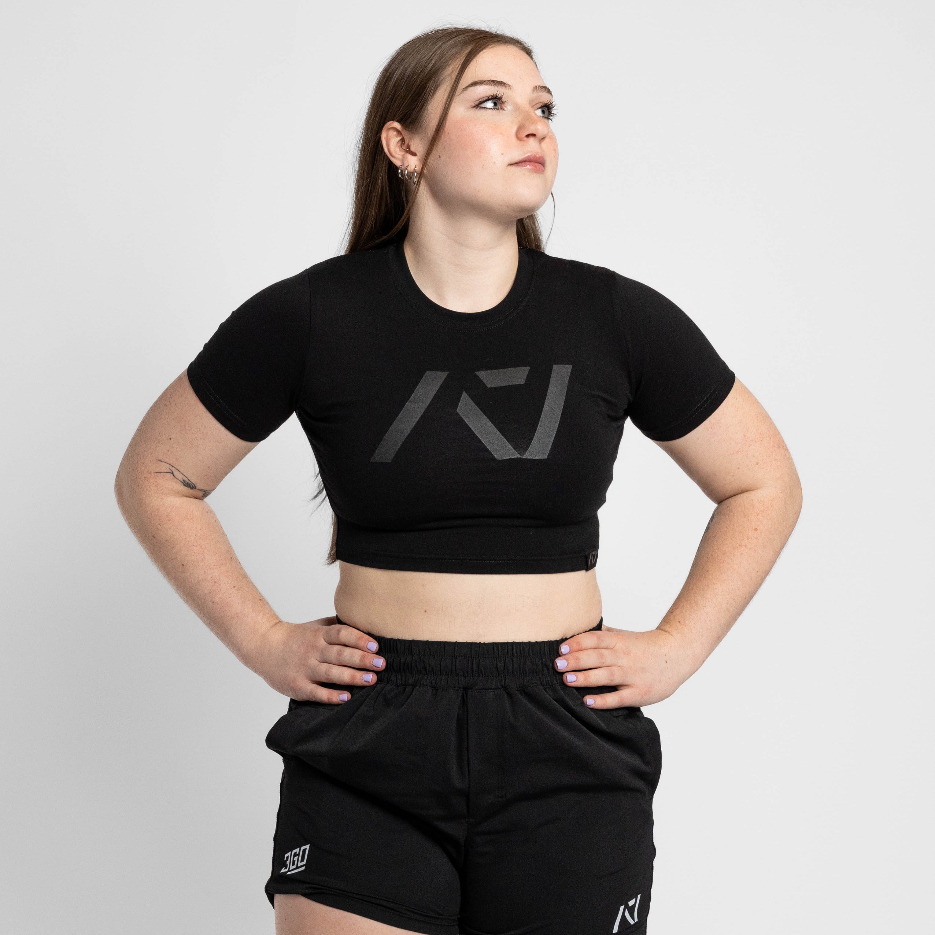 Person wearing a black crop top and shorts with a logo on a white background