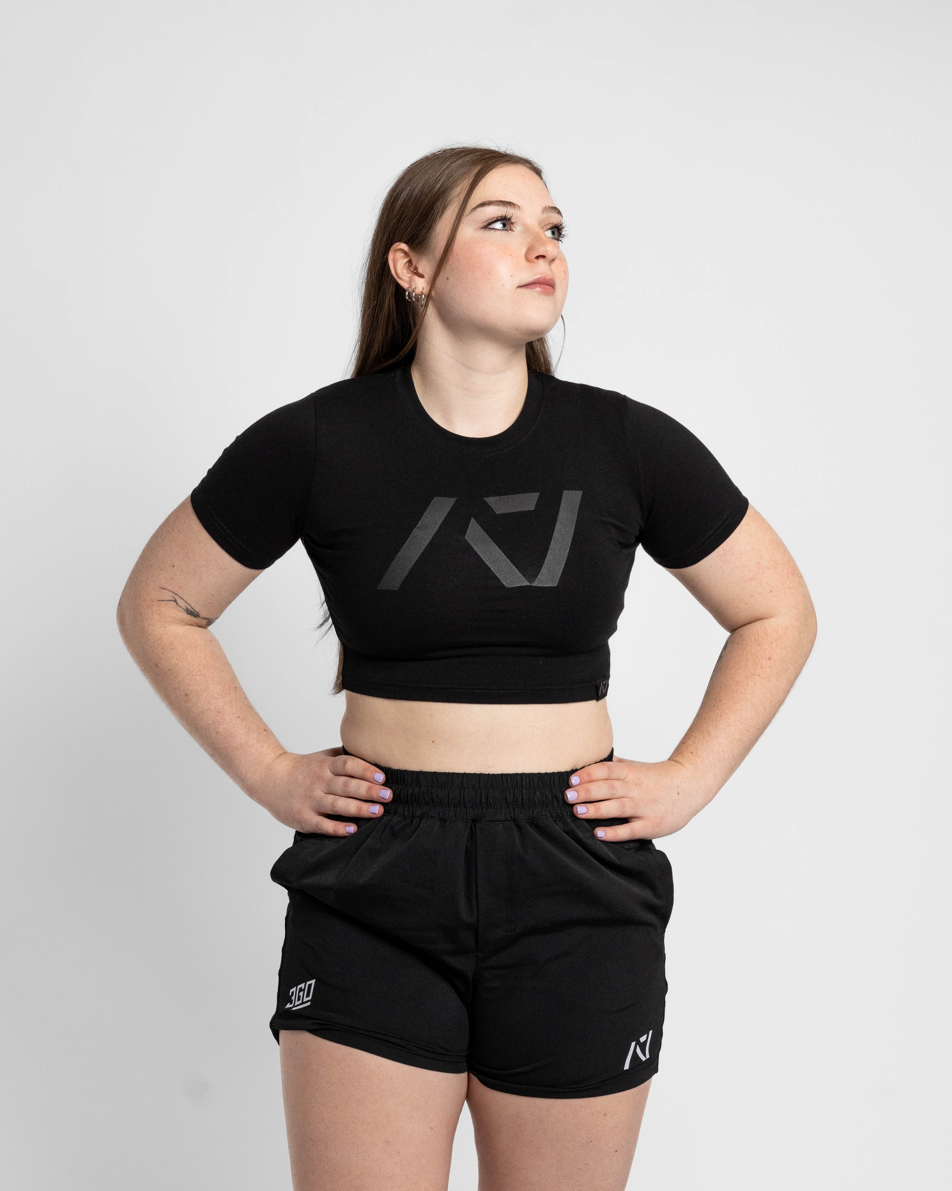Person wearing a black crop top and shorts with a logo on a white background