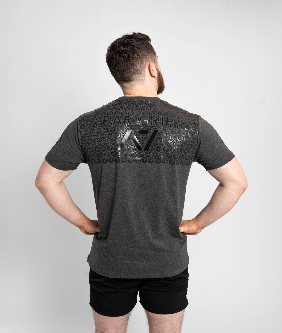 Man wearing a gray t-shirt with a7 bar grip on the back against a white background