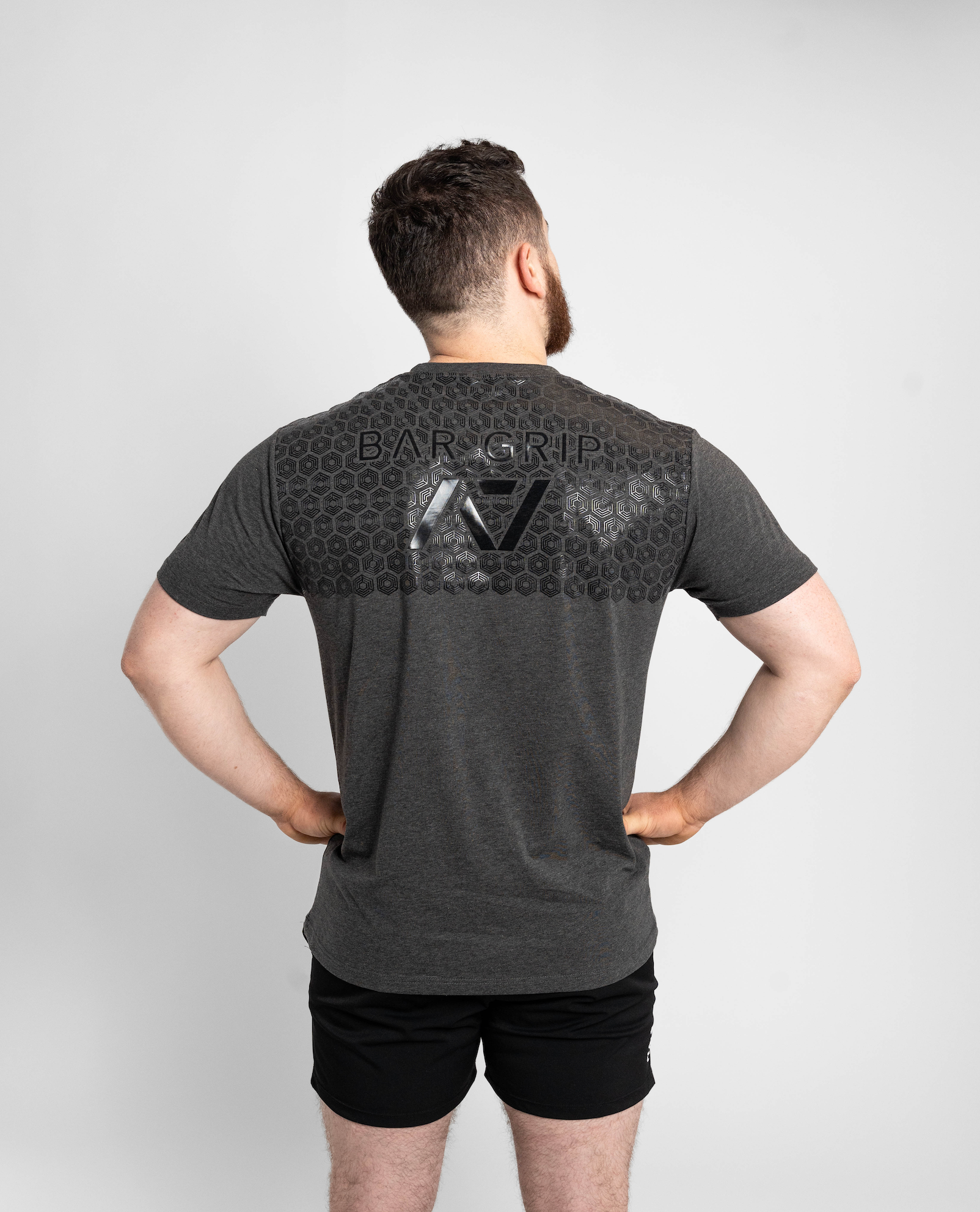 Man wearing a gray t-shirt with a7 bar grip on the back against a white background