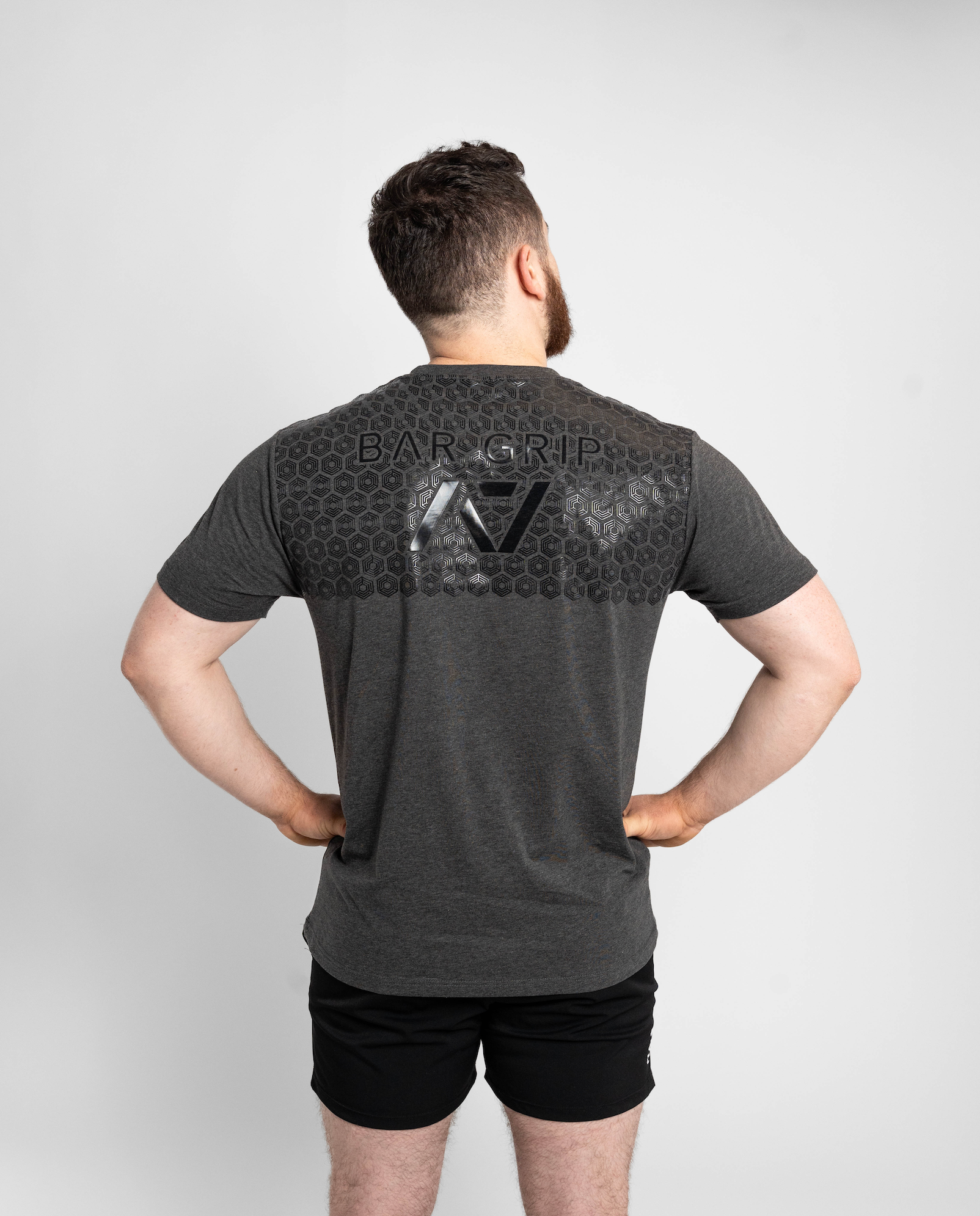 Man wearing a gray t-shirt with a7 bar grip on the back against a white background
