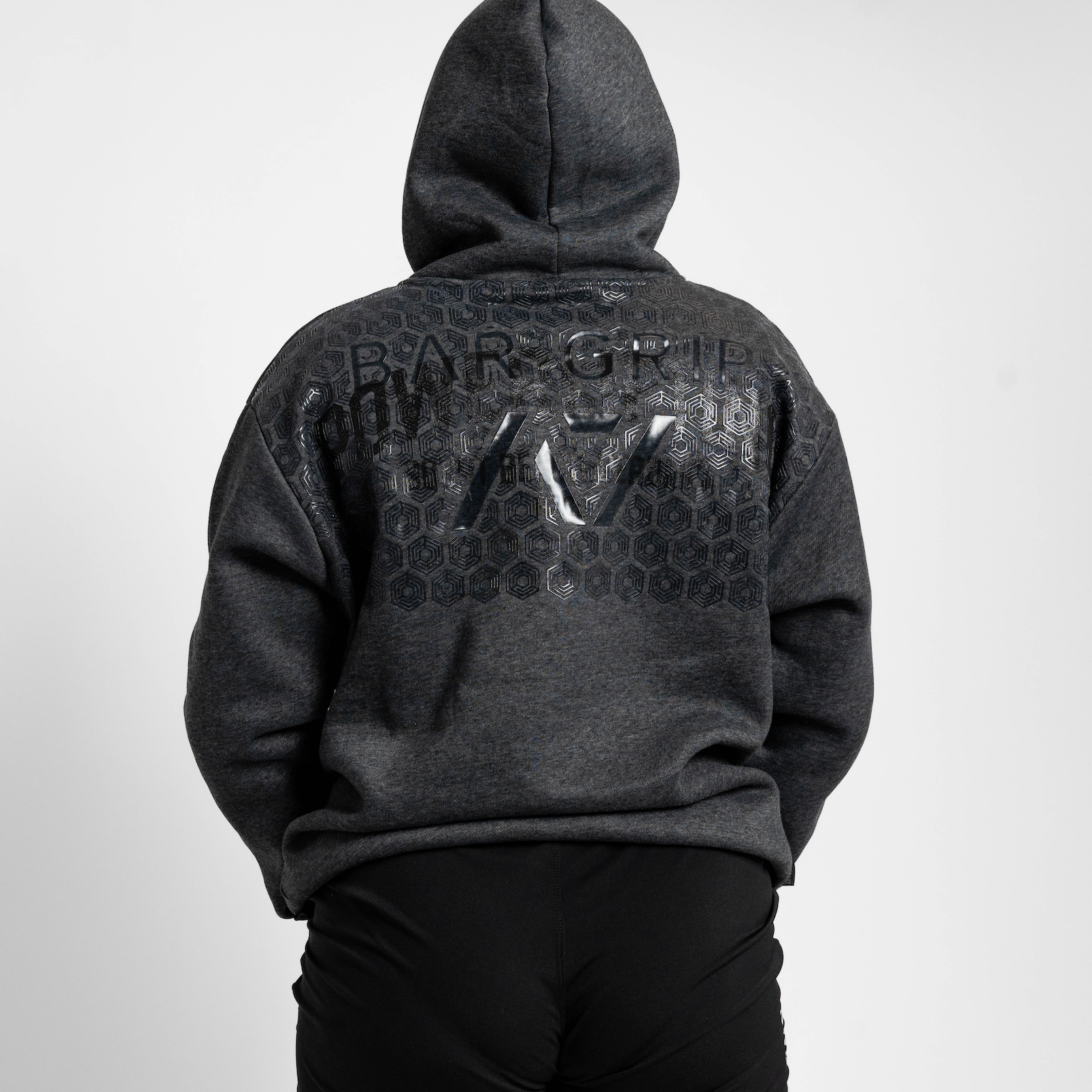 Person wearing a dark gray hoodie with branding on the back against a light gray background