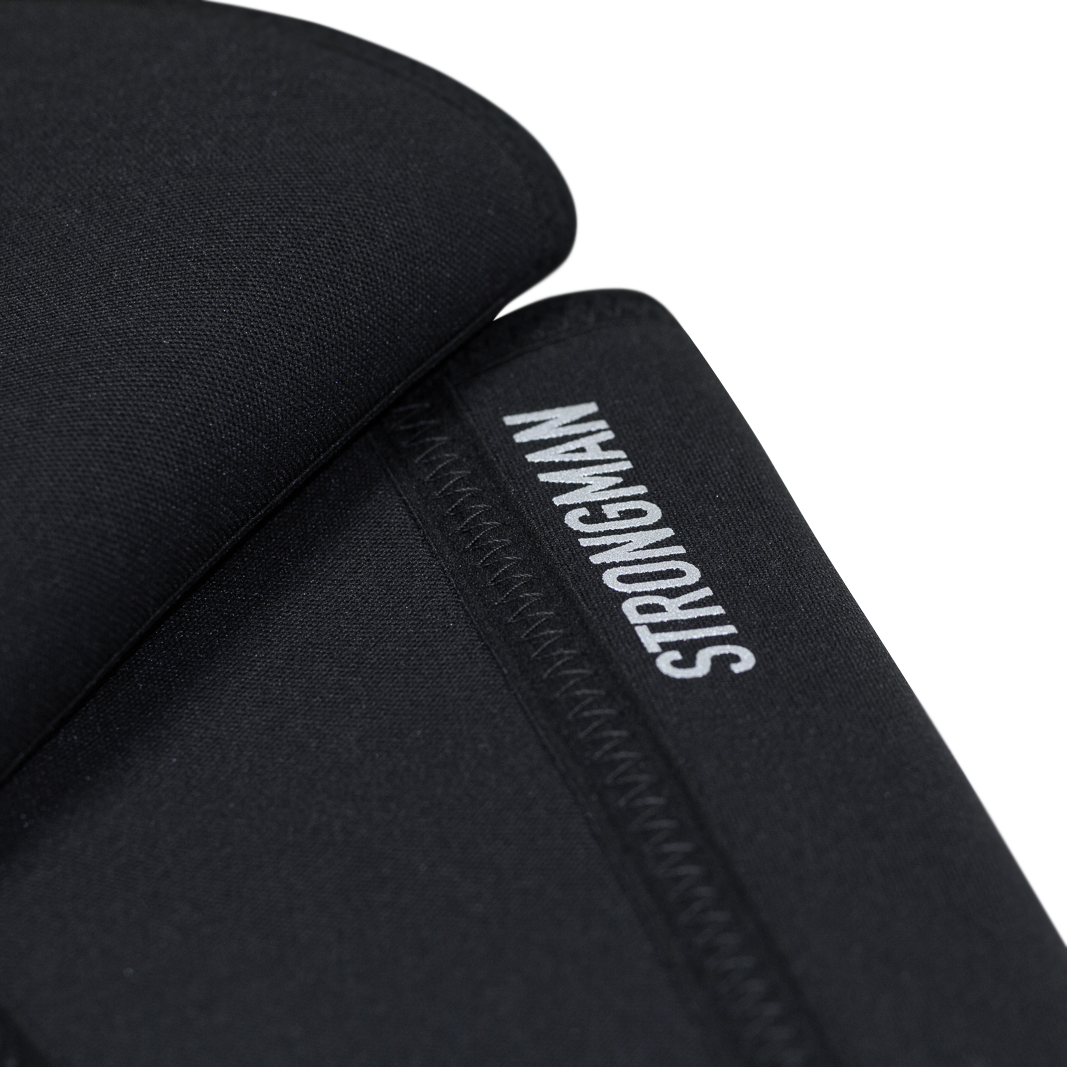 Detailed view of the reflective "Strongman" text on the black knee sleeves, emphasizing branding and design.