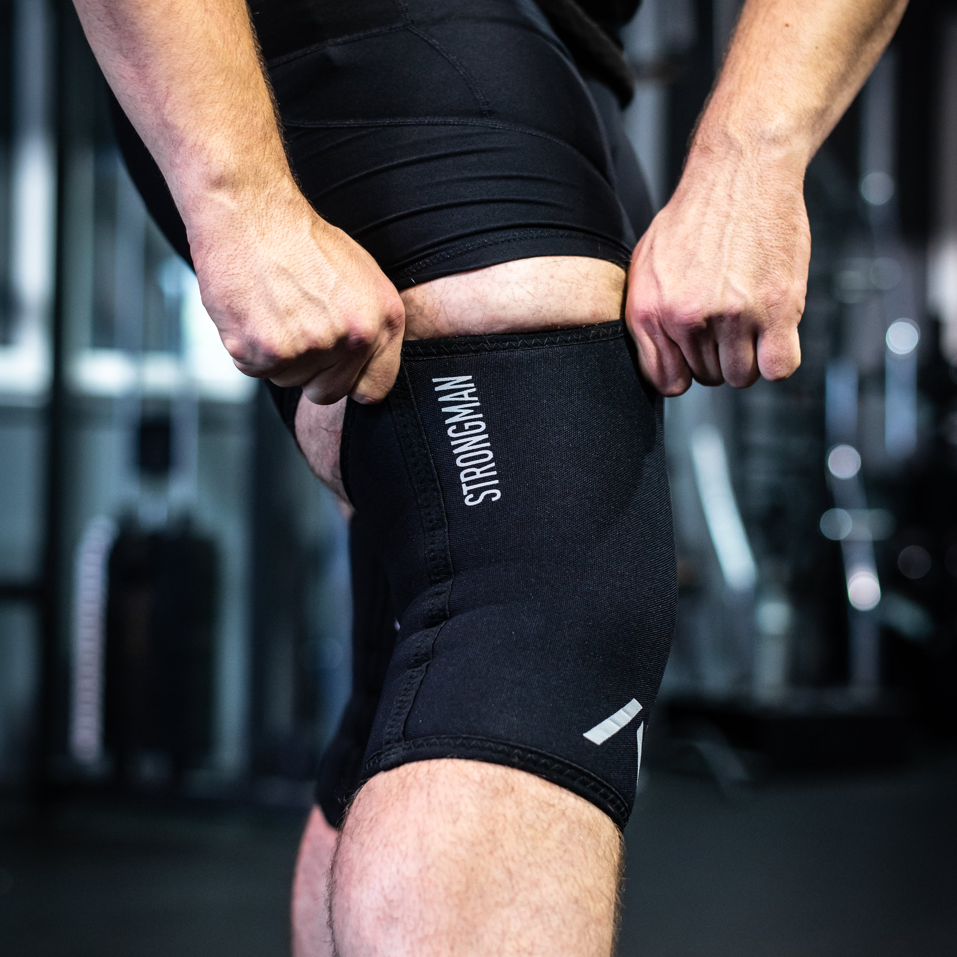 Detailed view of the reflective A7 logo and "Strongman" text on the black knee sleeves, emphasizing branding and design.