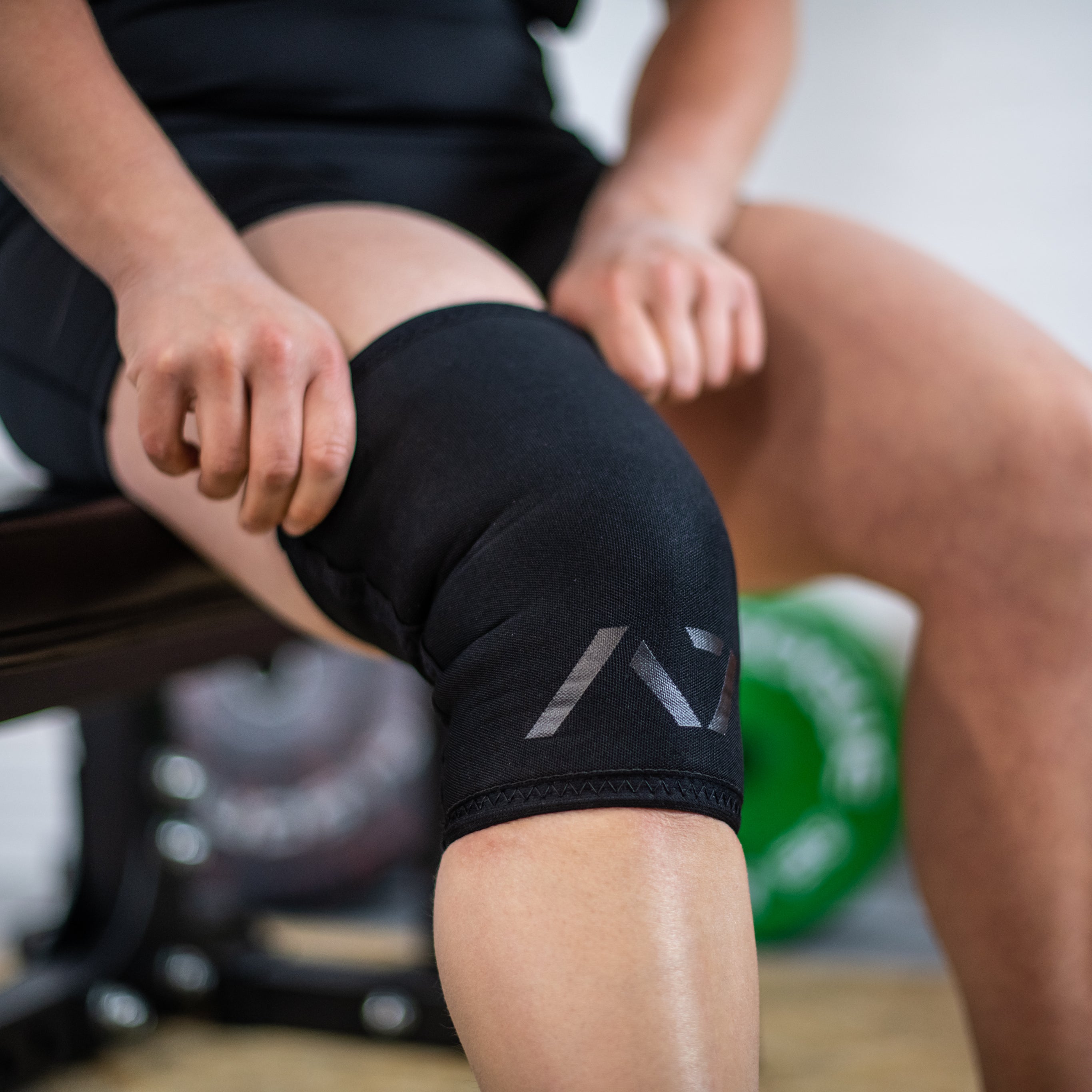 Athlete wearing A7 Stealth Stiff CONE Knee Sleeves during squat, demonstrating fit and support.