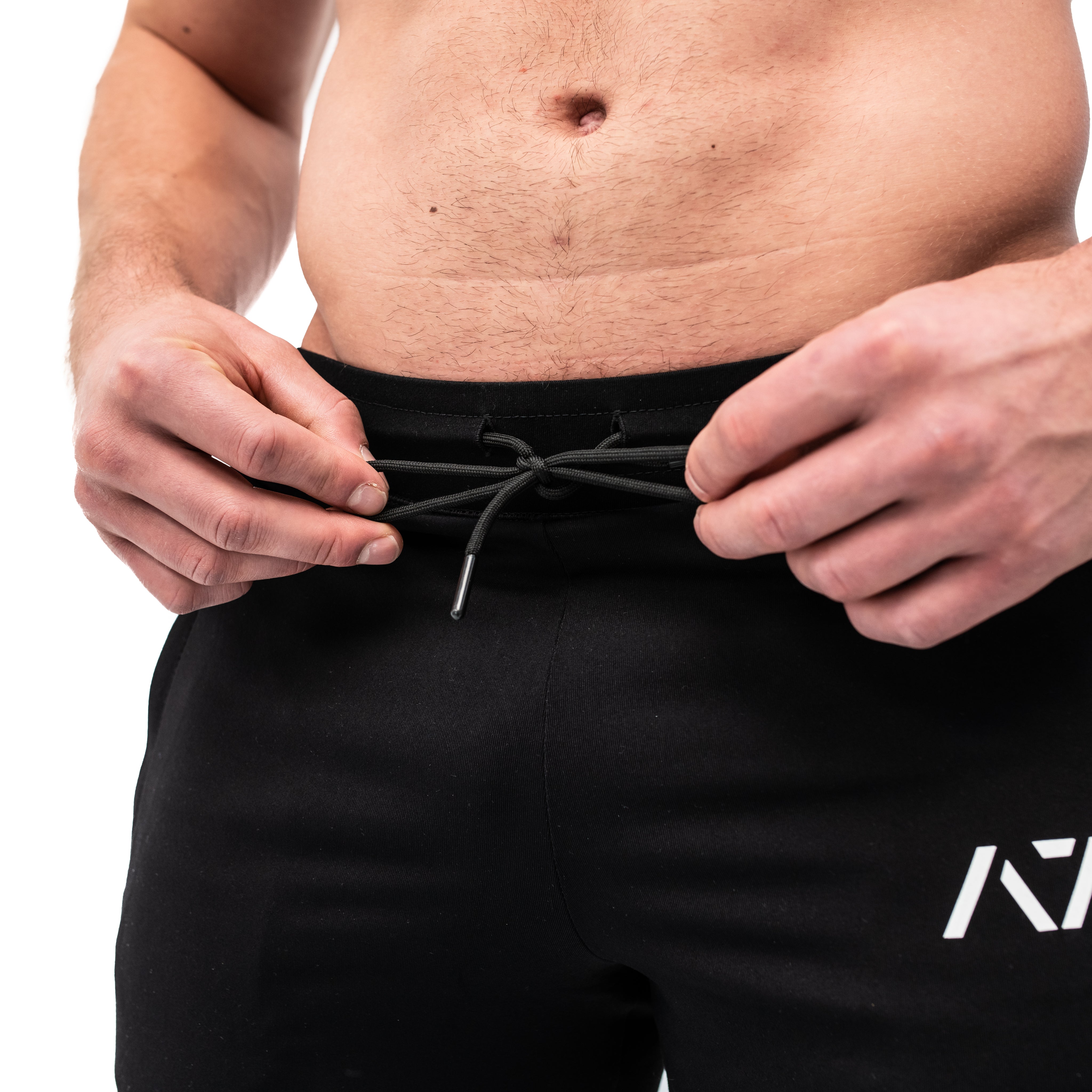 Close-up of the adjustable drawstring waistband on the Defy Joggers – Black, featuring flat laces for a secure fit and matte-finished eyelets for durability.