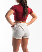 Back of female model wearing the ivory shorts with the red inner liner