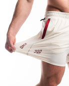 Show casing the stretch of 360Go 1Z Shorts in Ivory with red accents