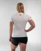 Person wearing a white athletic shirt with a logo on the back, standing against a plain background