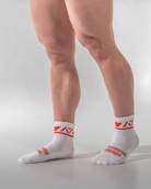White socks with red logo worn by a person on a light gray background
