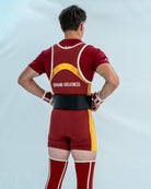 Male model wearing a red and yellow powerlifting singlet with 'Demand Greatness' on the back of the singlet on a light grey background