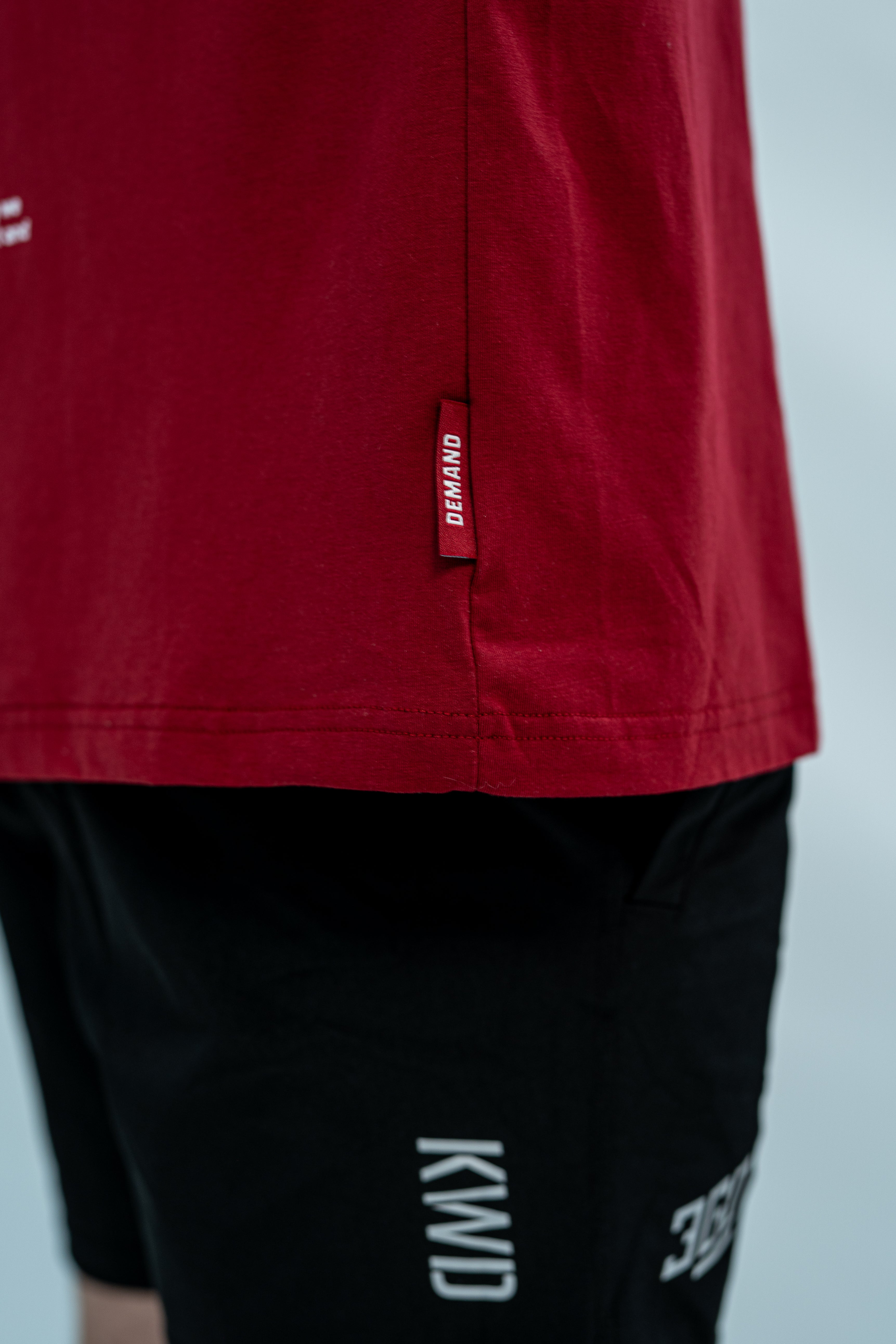 Red Over-fit Unisex shirt with a brand hem tag and featured with black 360Go KWD shorts with branding on a light gray background