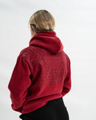 Female wearing a red hoodie with a Bar Grip Technology on the upper back against a white background