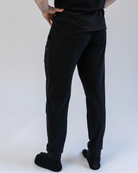 Person wearing black pants and a black shirt on a white background