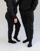 Two people wearing black tracksuits on a white background